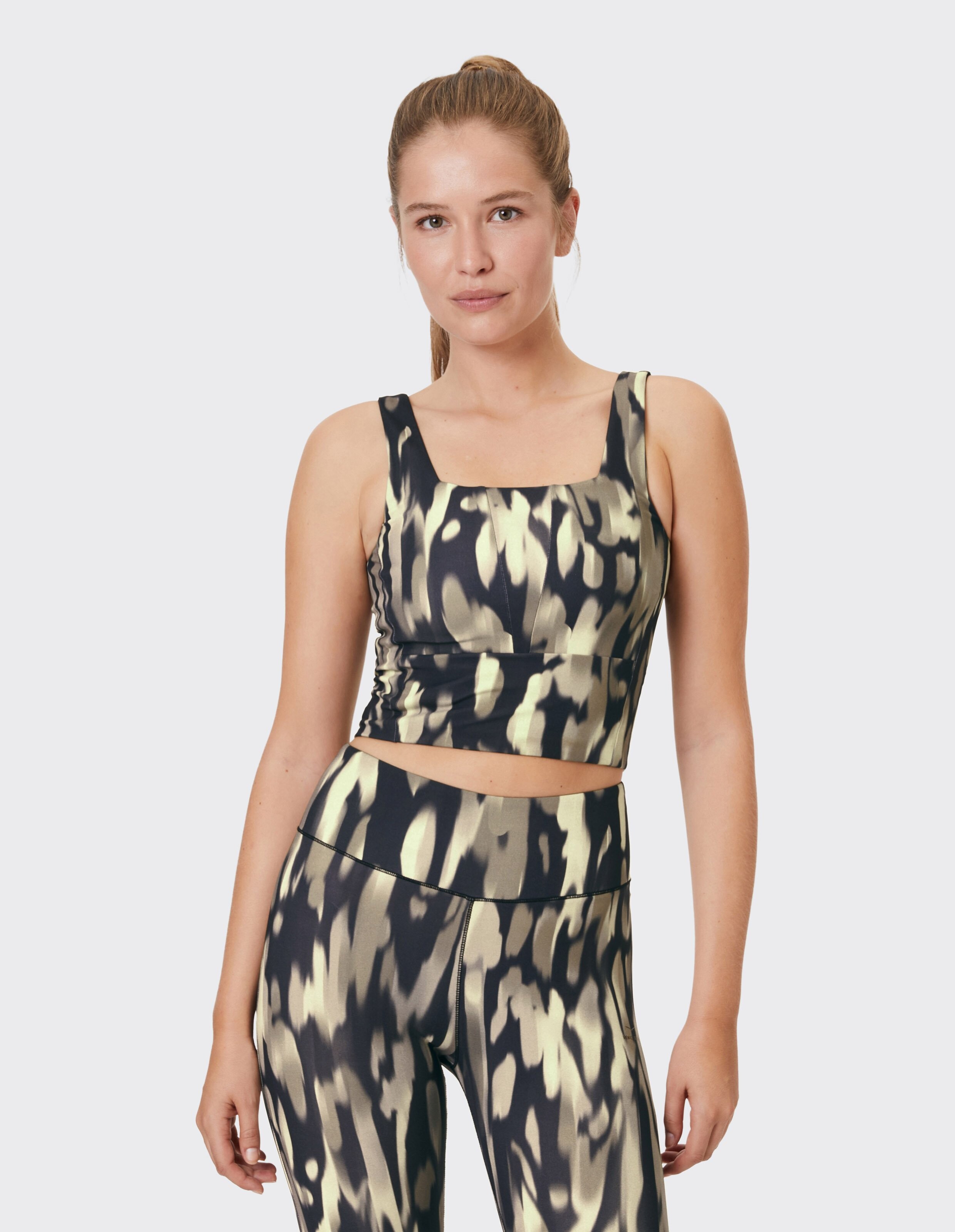 Frau trägt ein stilvolles, schwarz-beige gemustertes Crop-Top für lässige Lounge-Kleidung.