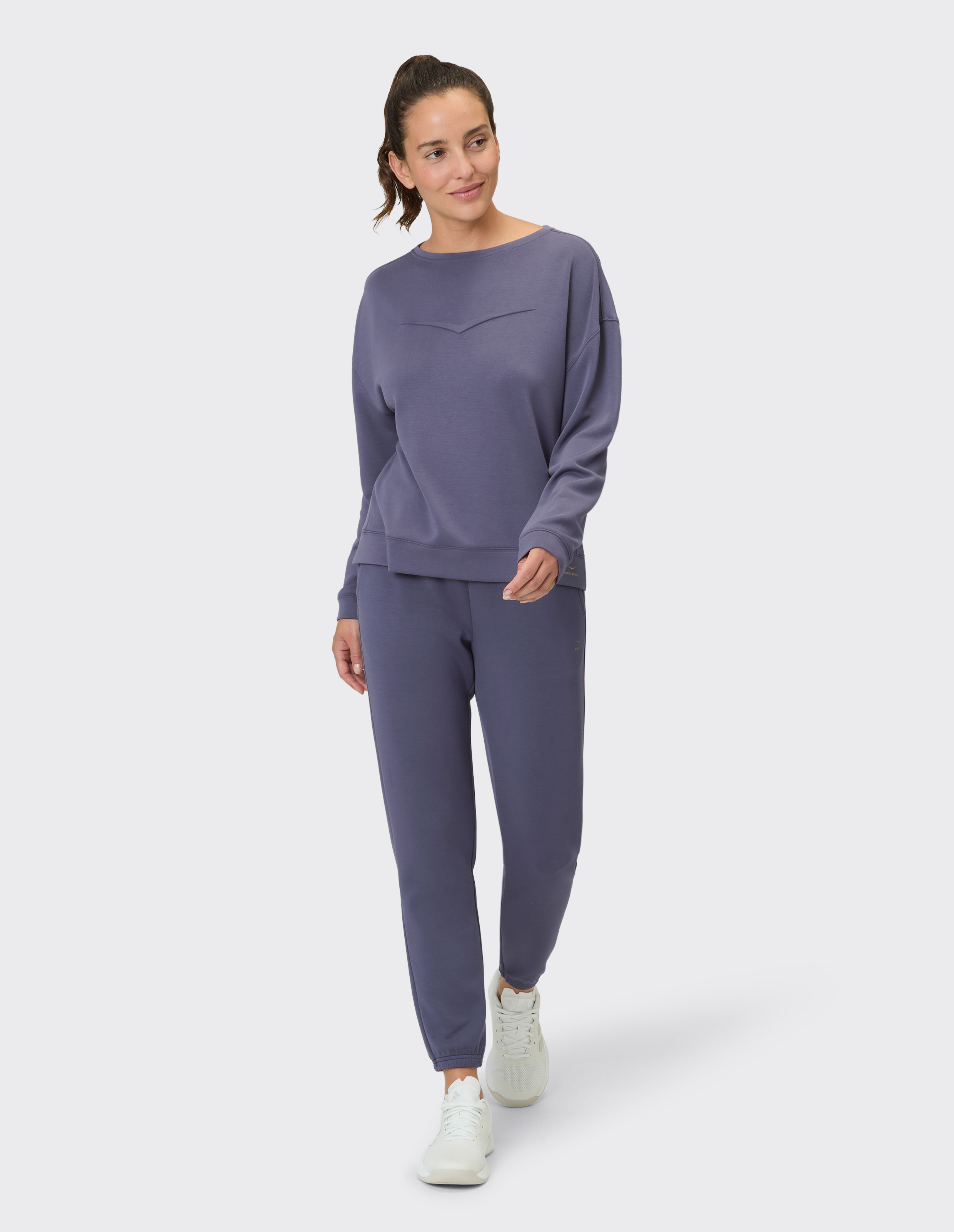Frau in gemütlichem lila Sweatshirt und passender Jogginghose, perfekt für Freizeitkleidung.
