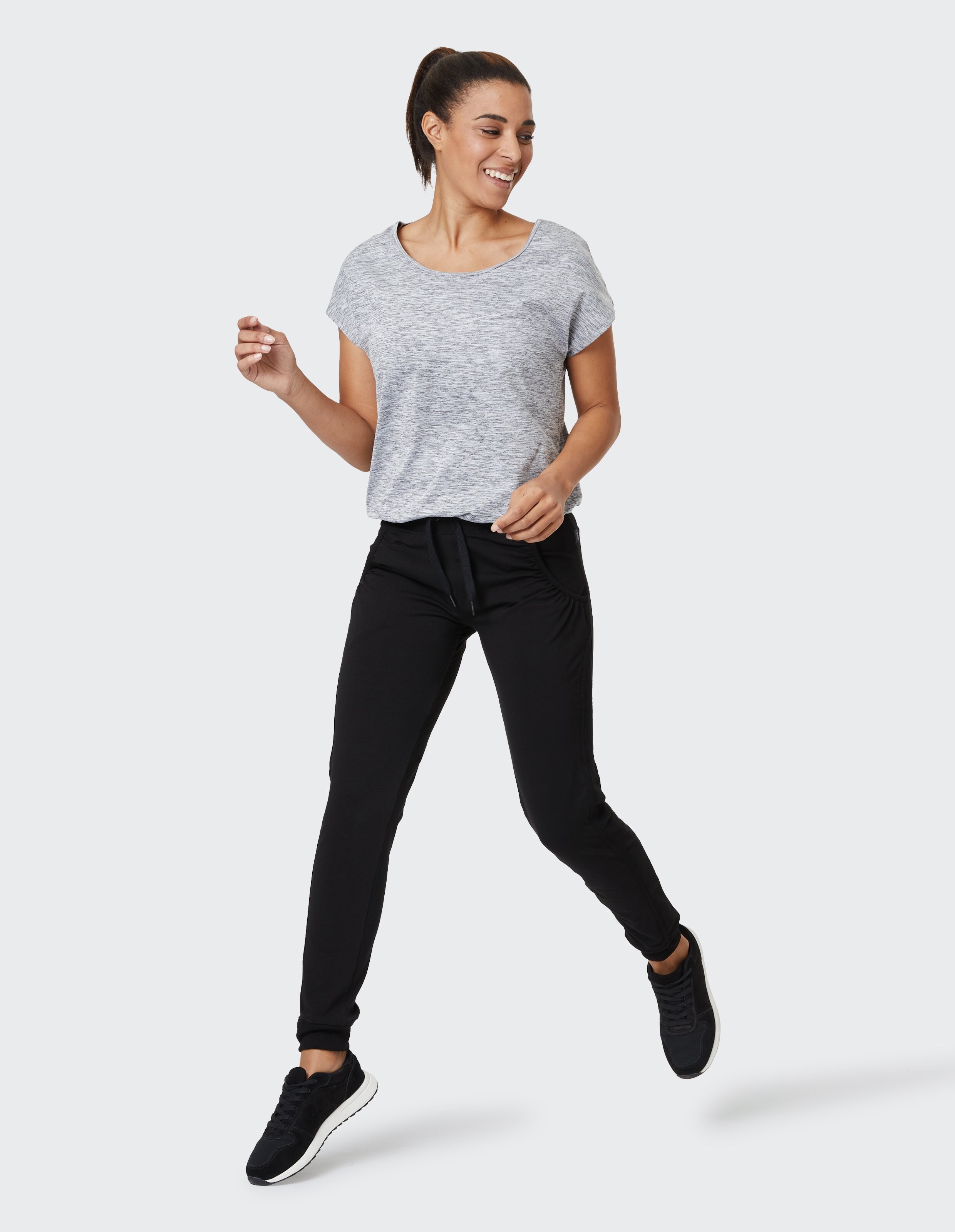 Frau trägt ein grau meliertes T-Shirt und schwarze lässige Jogginghosen für einen bequemen, stilvollen Look.
