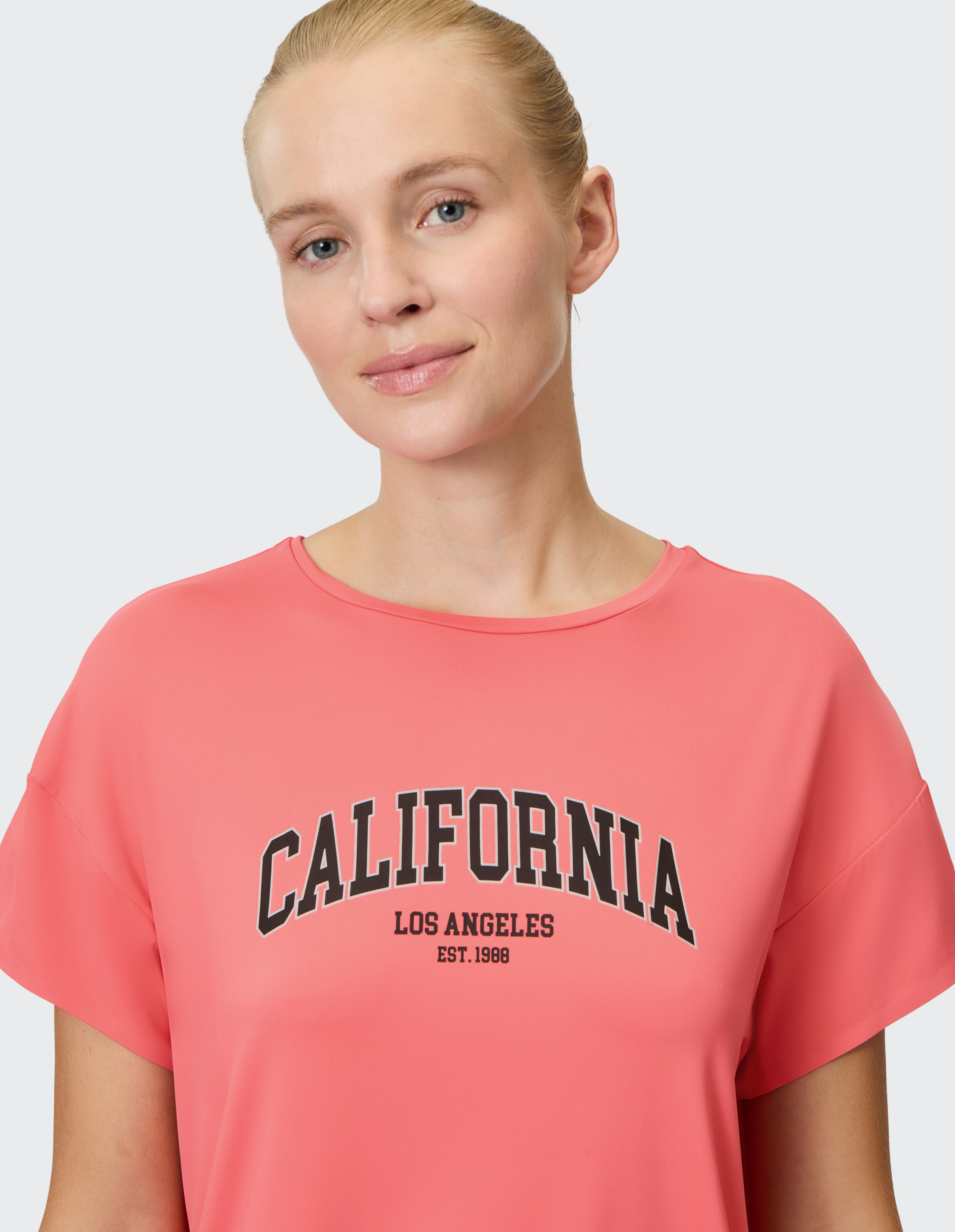 Frau trägt ein rosa T-Shirt mit California-Grafik, perfekt für Freizeitausflüge.