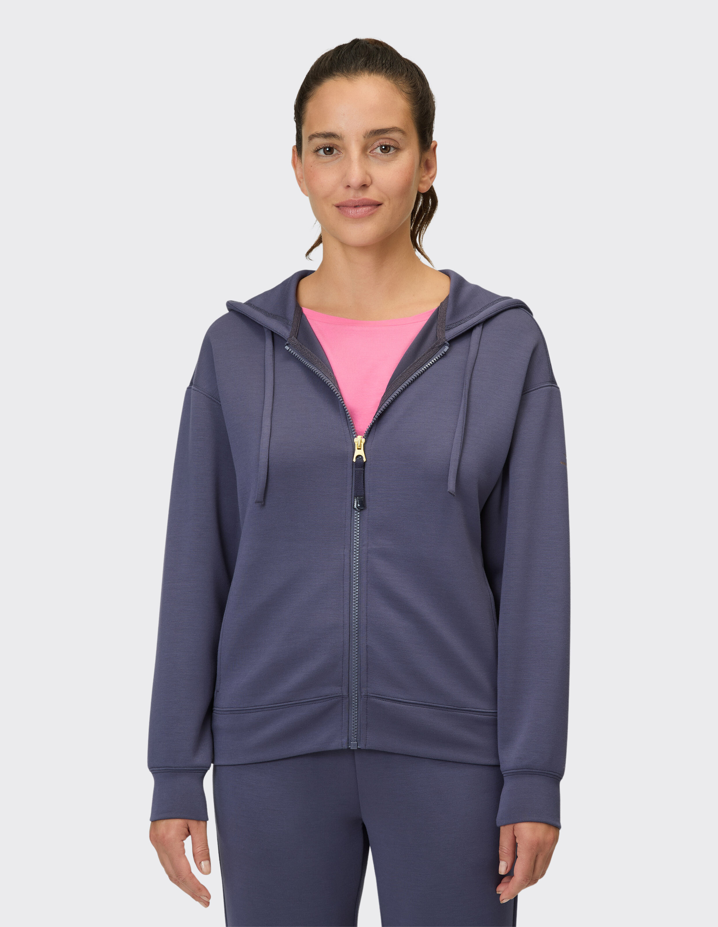 Frau trägt einen kuscheligen dunkelblauen Kapuzenpullover mit Reißverschluss über einem rosa Hemd für lässigen Stil.