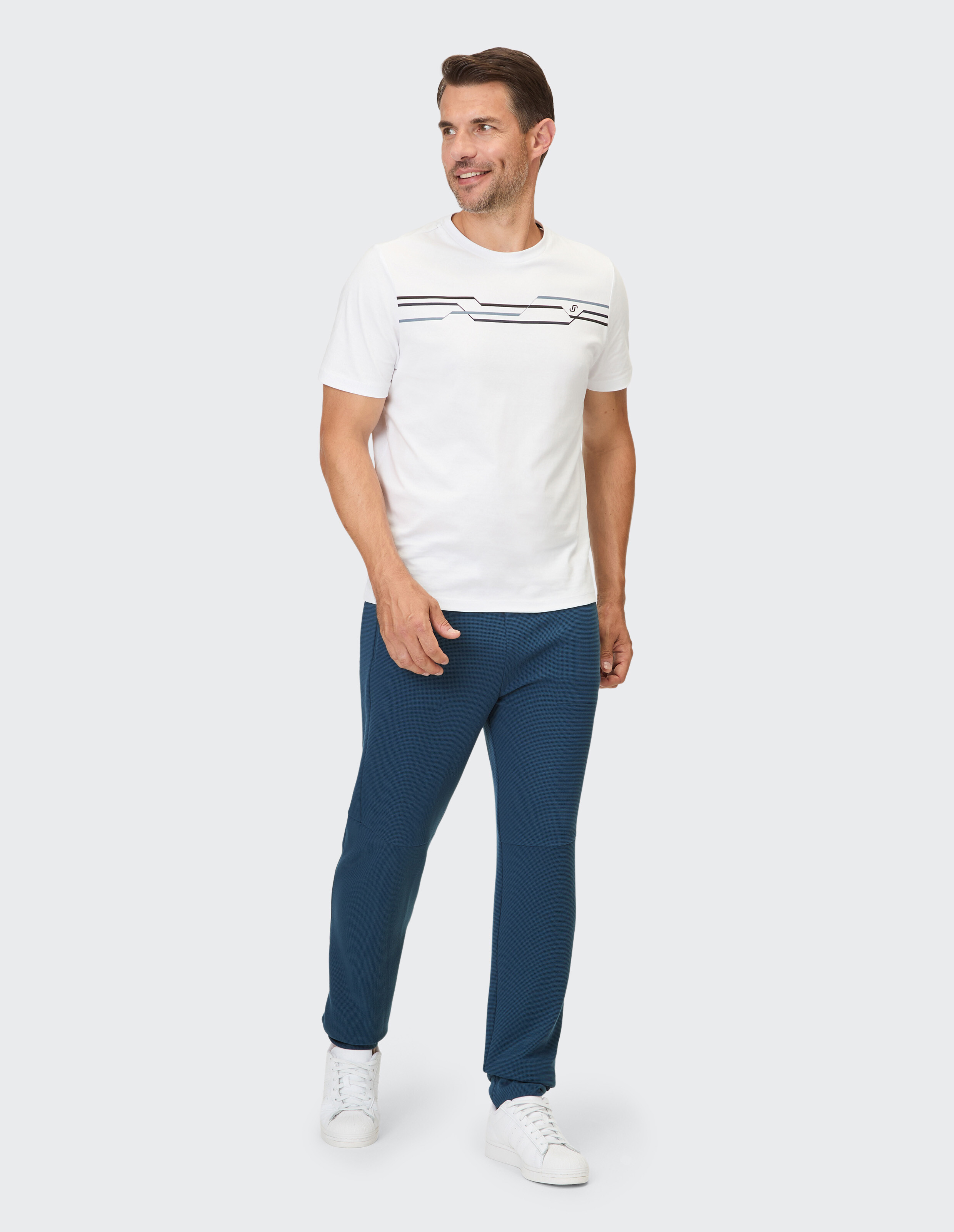 Mann in einem weiß gestreiften T-Shirt und einer dunkelblauen Hose, perfekt für Freizeitausflüge.