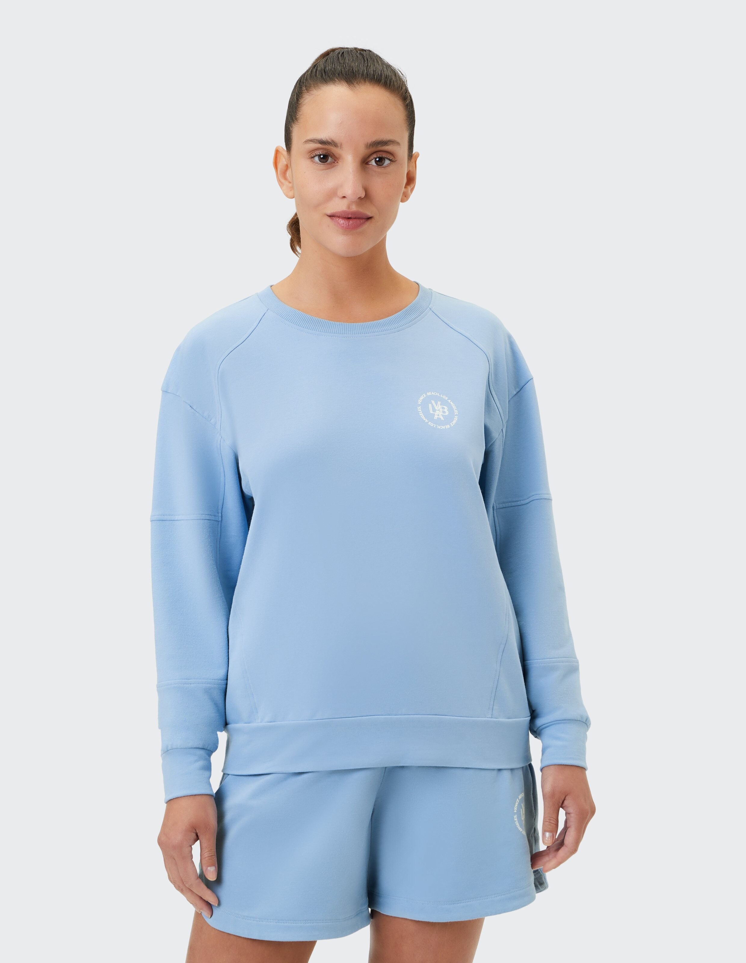 Frau trägt ein hellblaues Venice Beach Evalie-Sweatshirt für lässige Lounge-Kleidung.