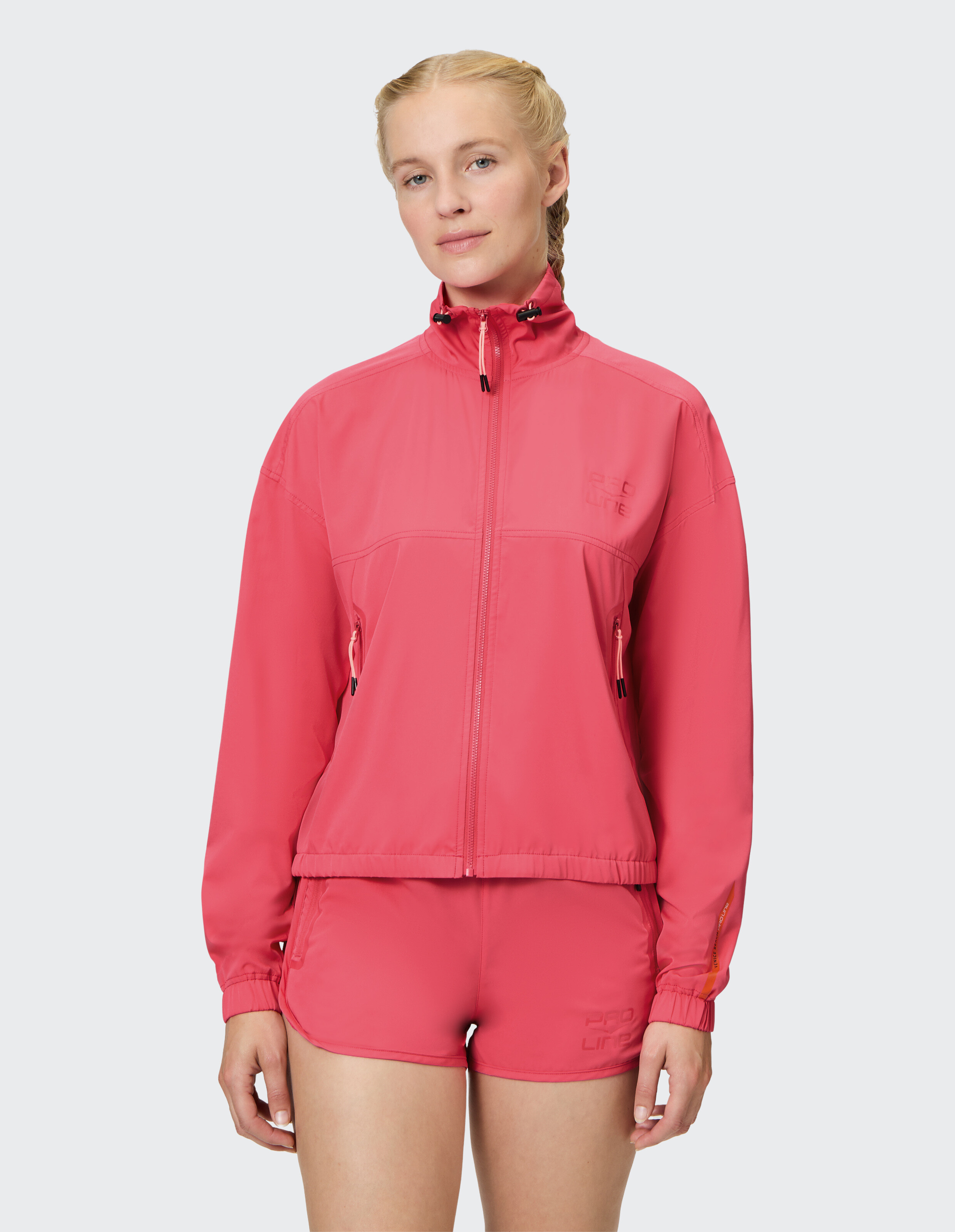 Frau trägt eine rosafarbene Venice Beach Funktionsjacke New Orleans und passende Shorts.