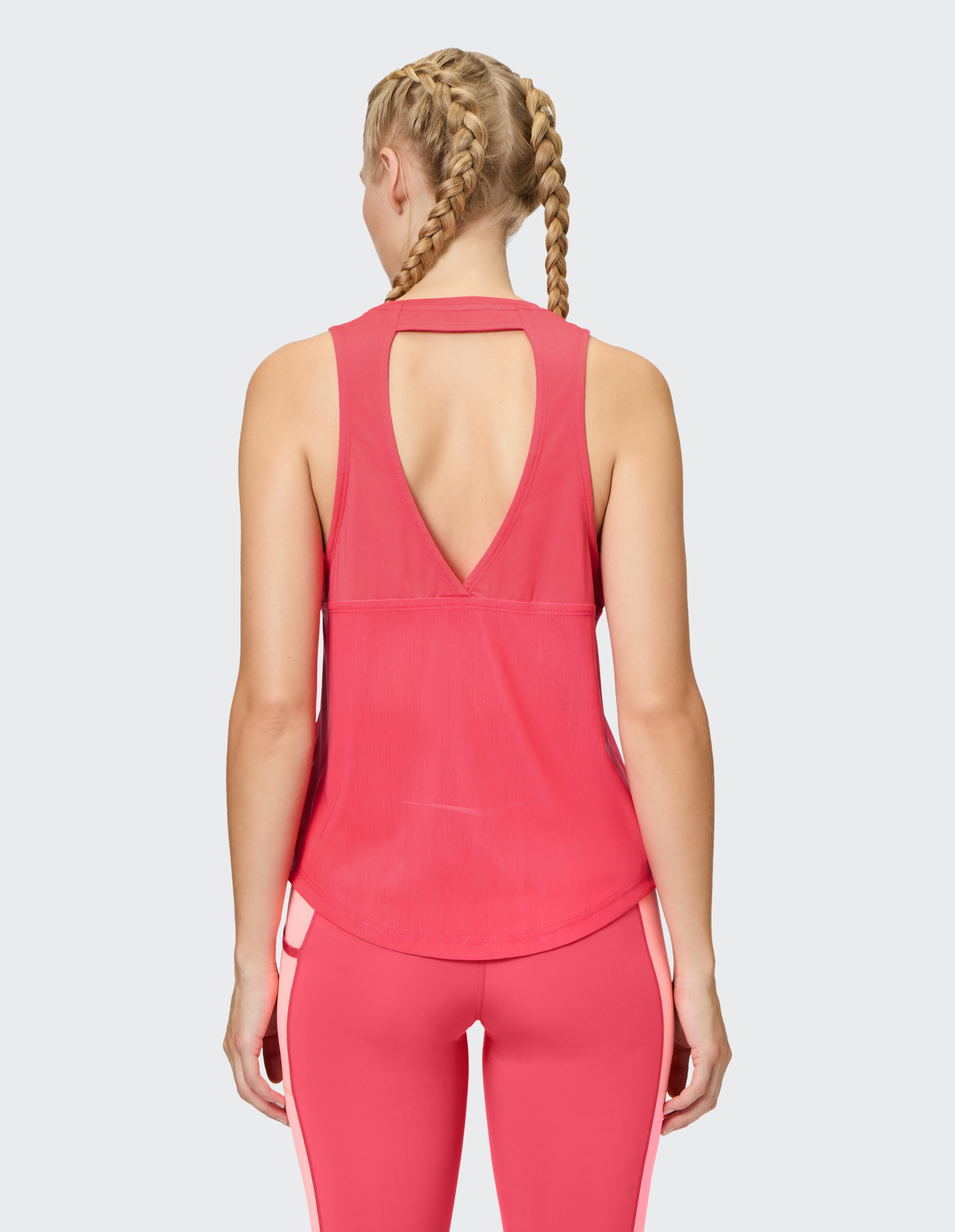 Rückansicht einer Frau in einem rosa ärmellosen Top und passenden Leggings.