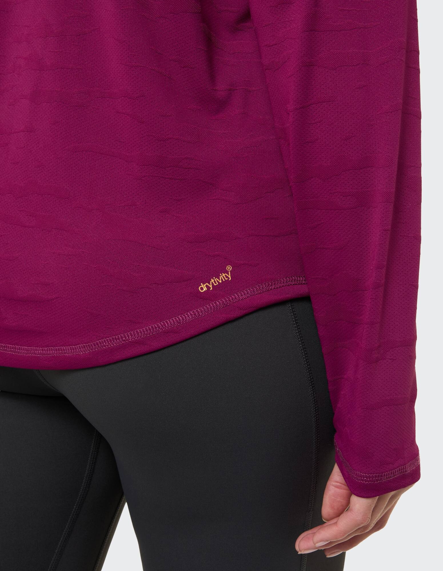 Nahaufnahme einer Frau, die ein lila Langarmshirt und schwarze Leggings trägt.