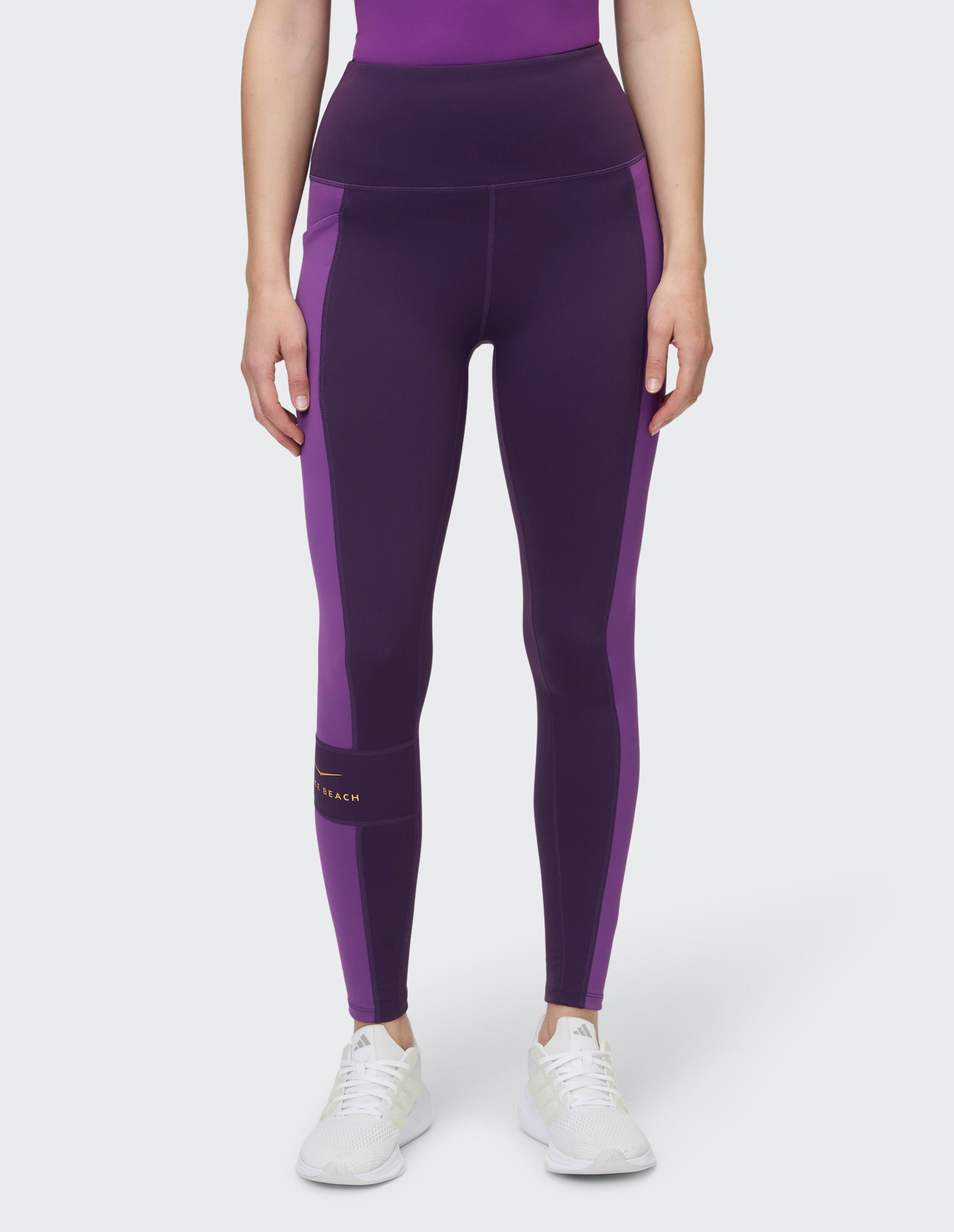 Frau trägt lila Leggings mit hoher Taille und Seiteneinsätzen für lässigen Komfort.