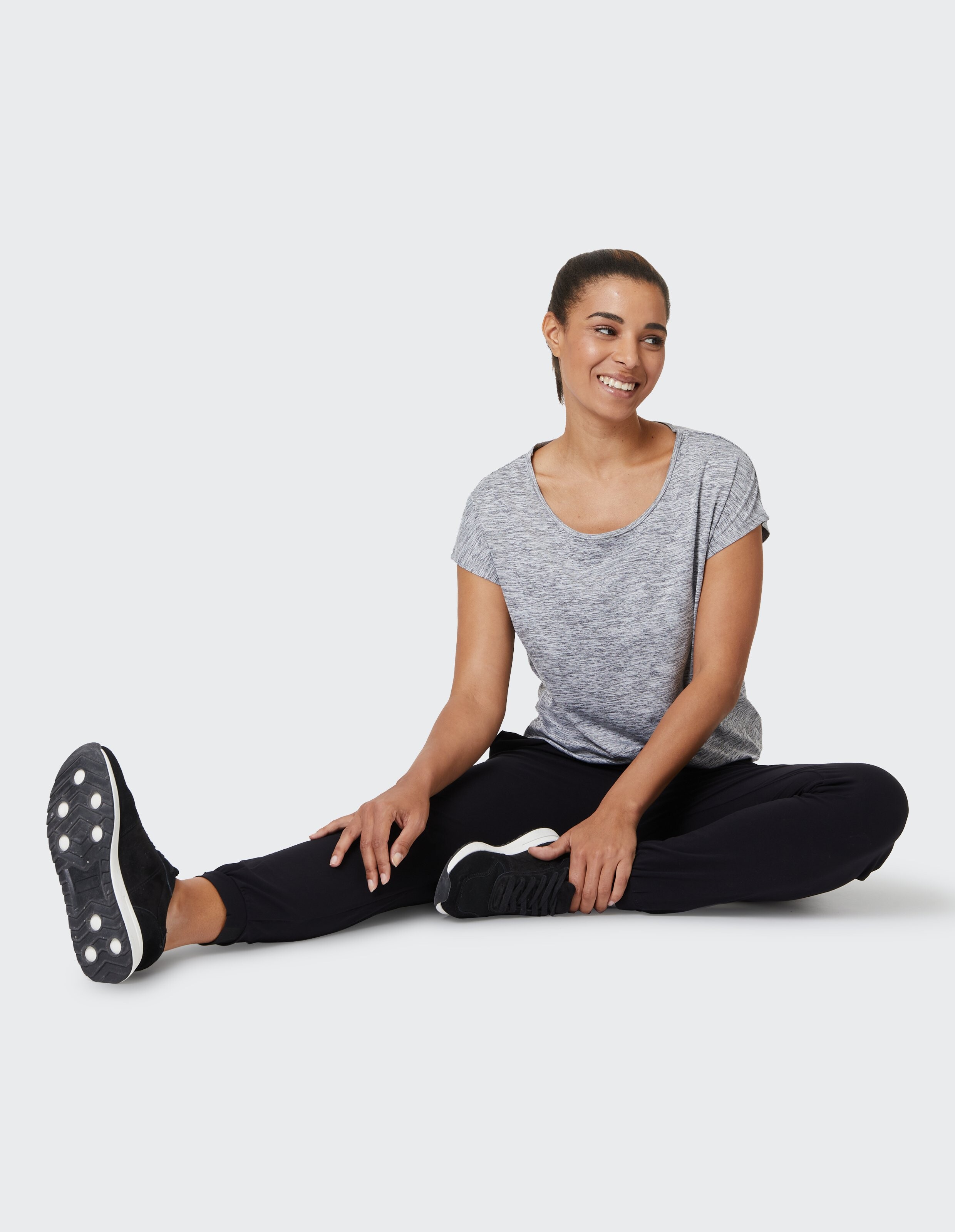 Frau trägt ein grau meliertes T-Shirt und schwarze Jogginghosen für einen gemütlichen, lässigen Look.