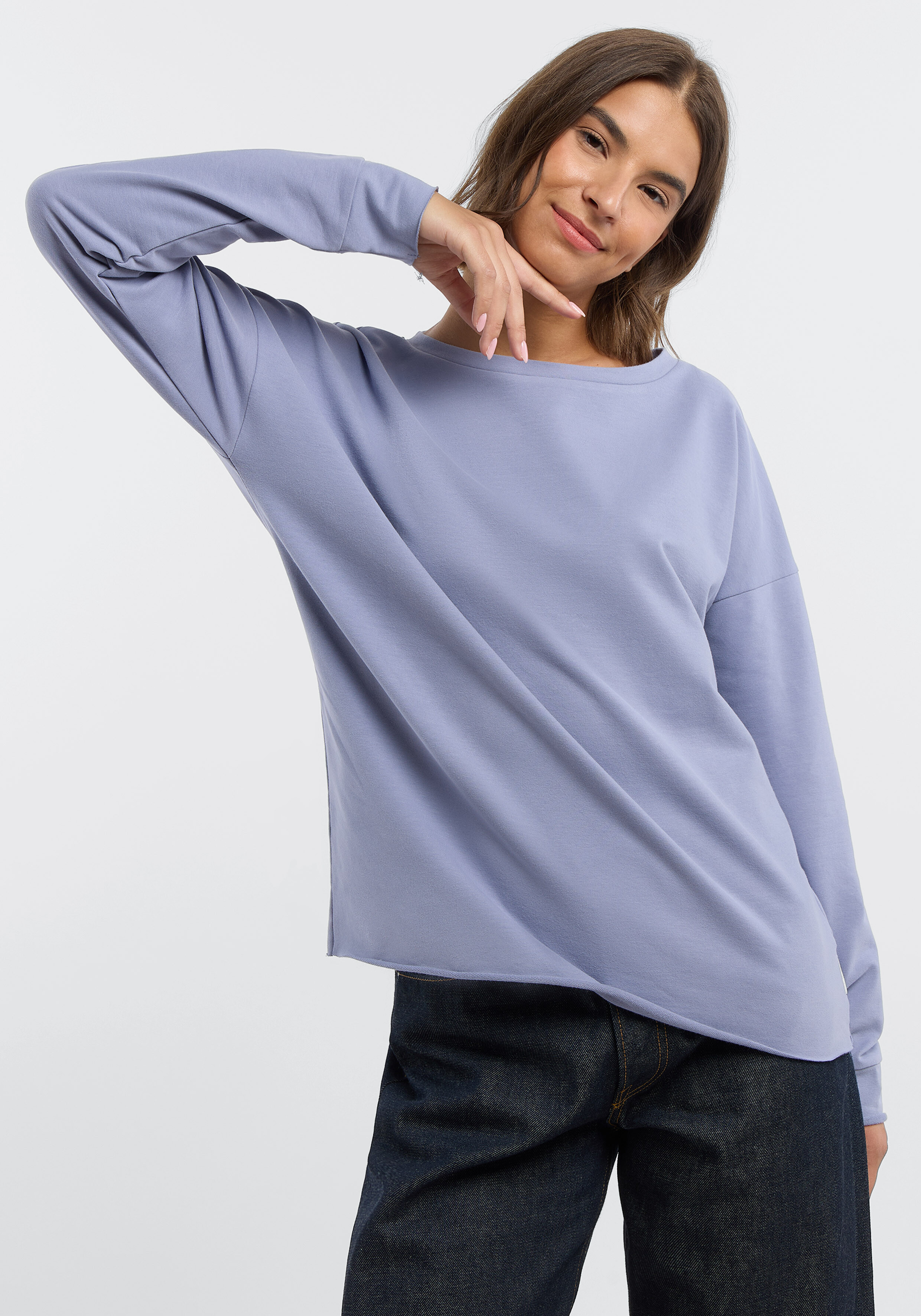 Frau trägt ein gemütliches, hellblaues, langärmliges Freizeit-Sweatshirt mit offenem Saum.