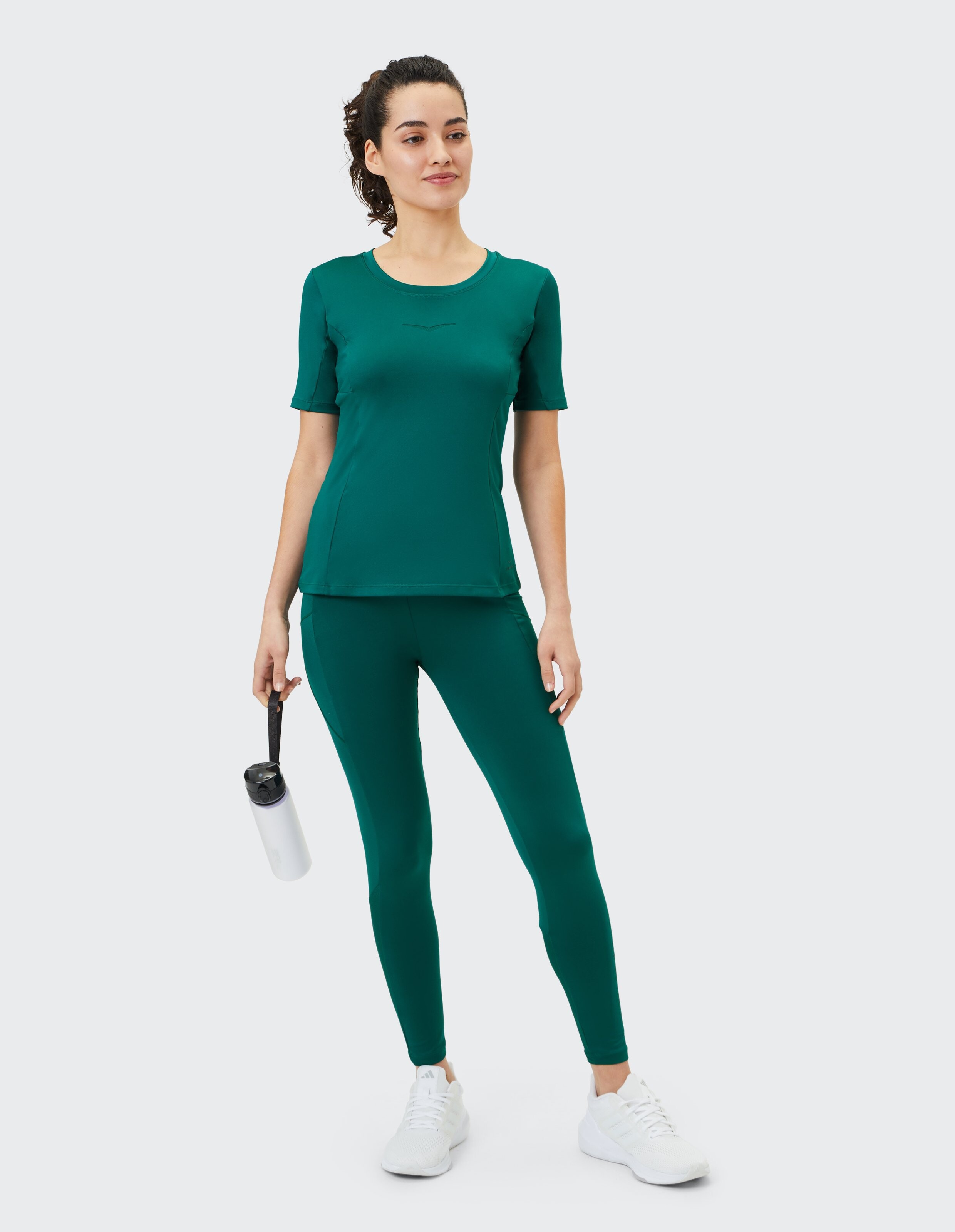 Frau in einem blaugrünen Activewear-Set, bestehend aus einem figurbetonten Oberteil und Leggings, perfekt für Freizeitausflüge.