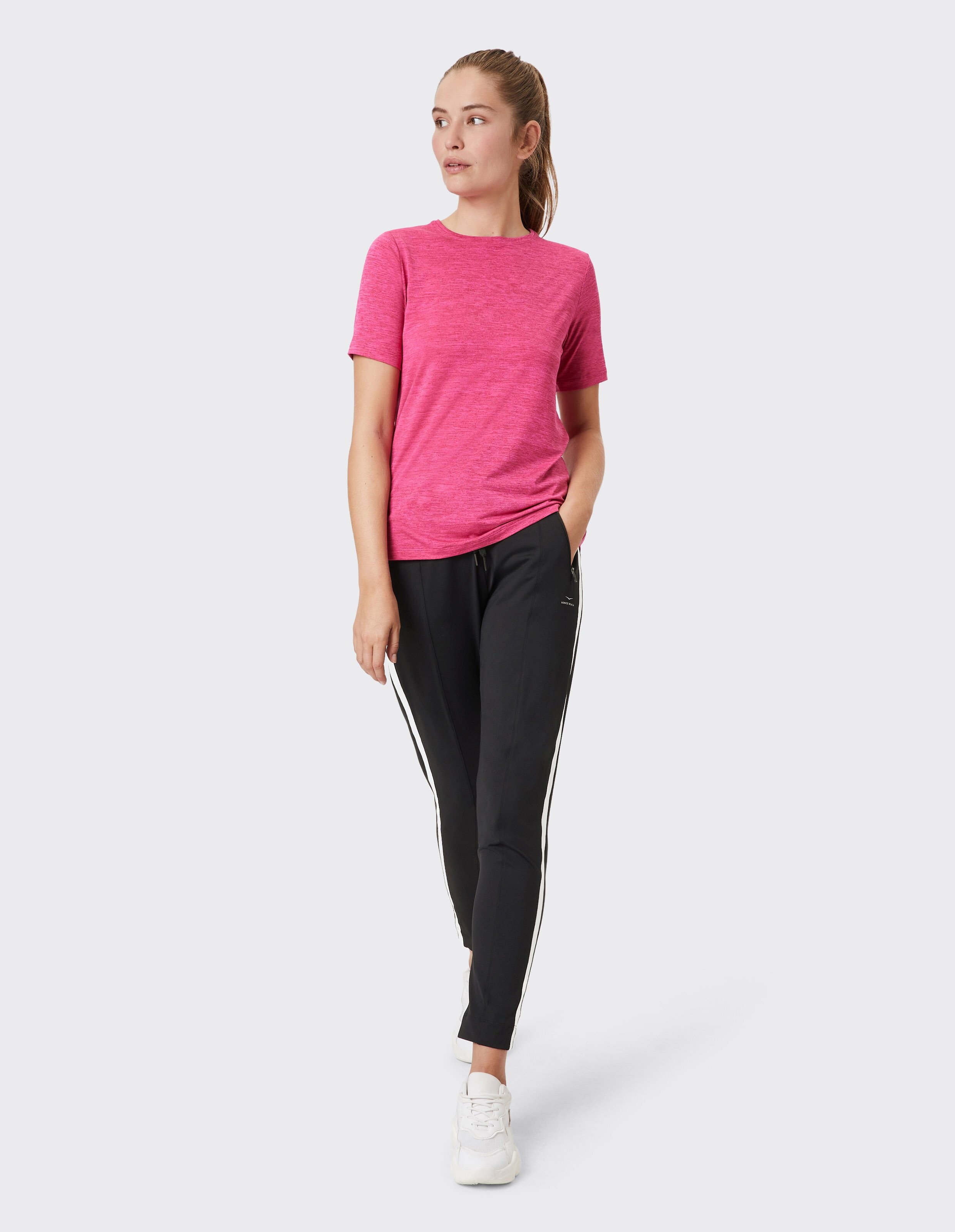 Frau trägt eine Jogginghose von Venice Beach Shenley und ein rosa T-Shirt für einen lässigen Stil.