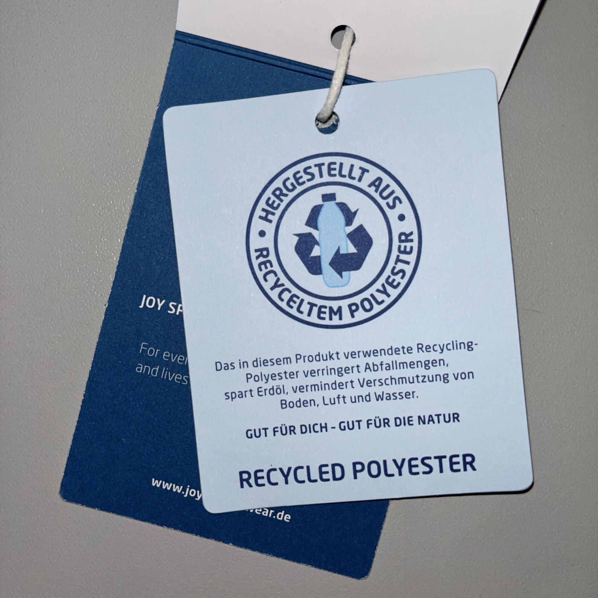 Etikett mit Informationen zu recyceltem Polyester für umweltfreundliche Freizeitkleidung.