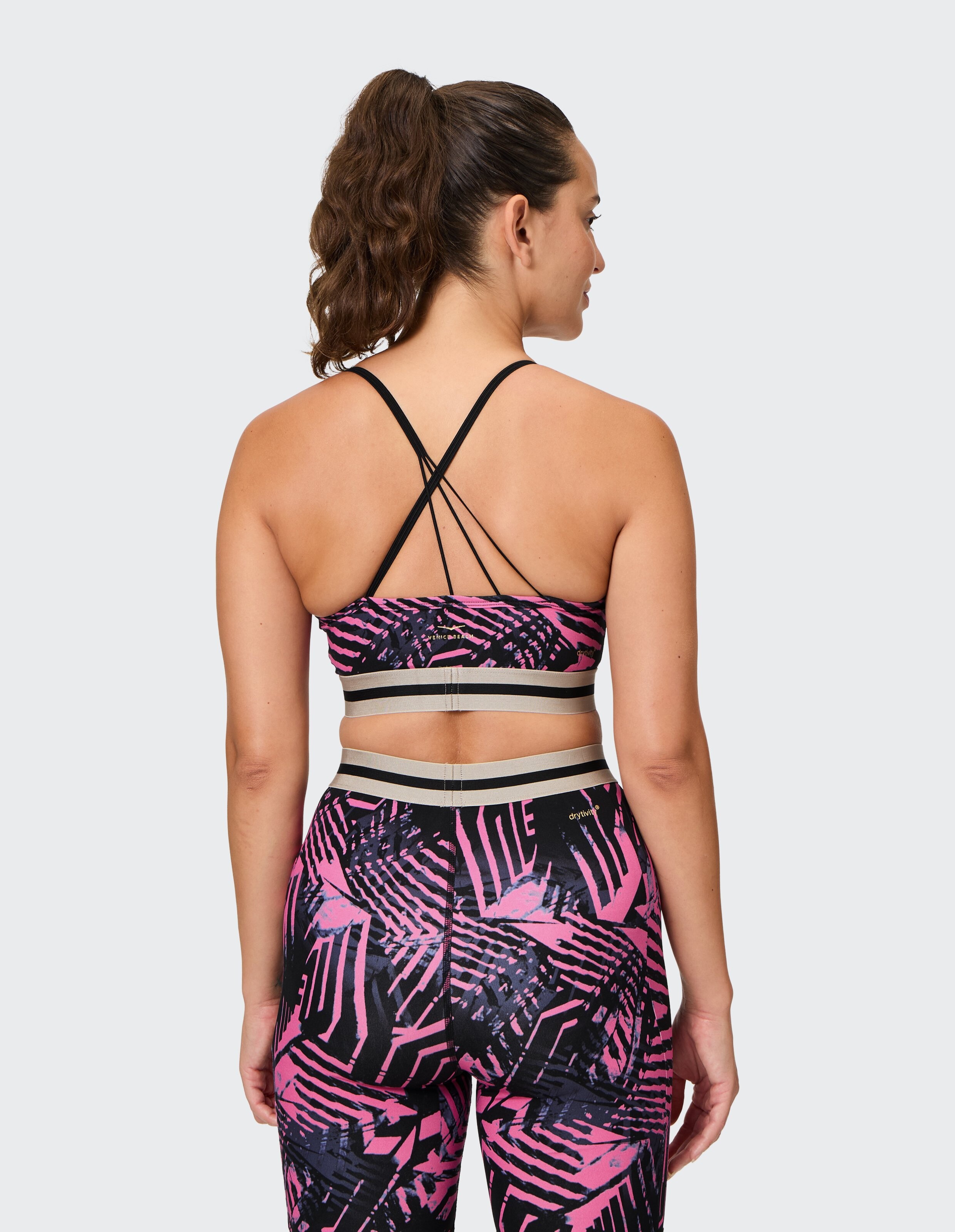 Rückansicht einer Frau in einem rosa und schwarz gemusterten Sport-BH und Leggings.
