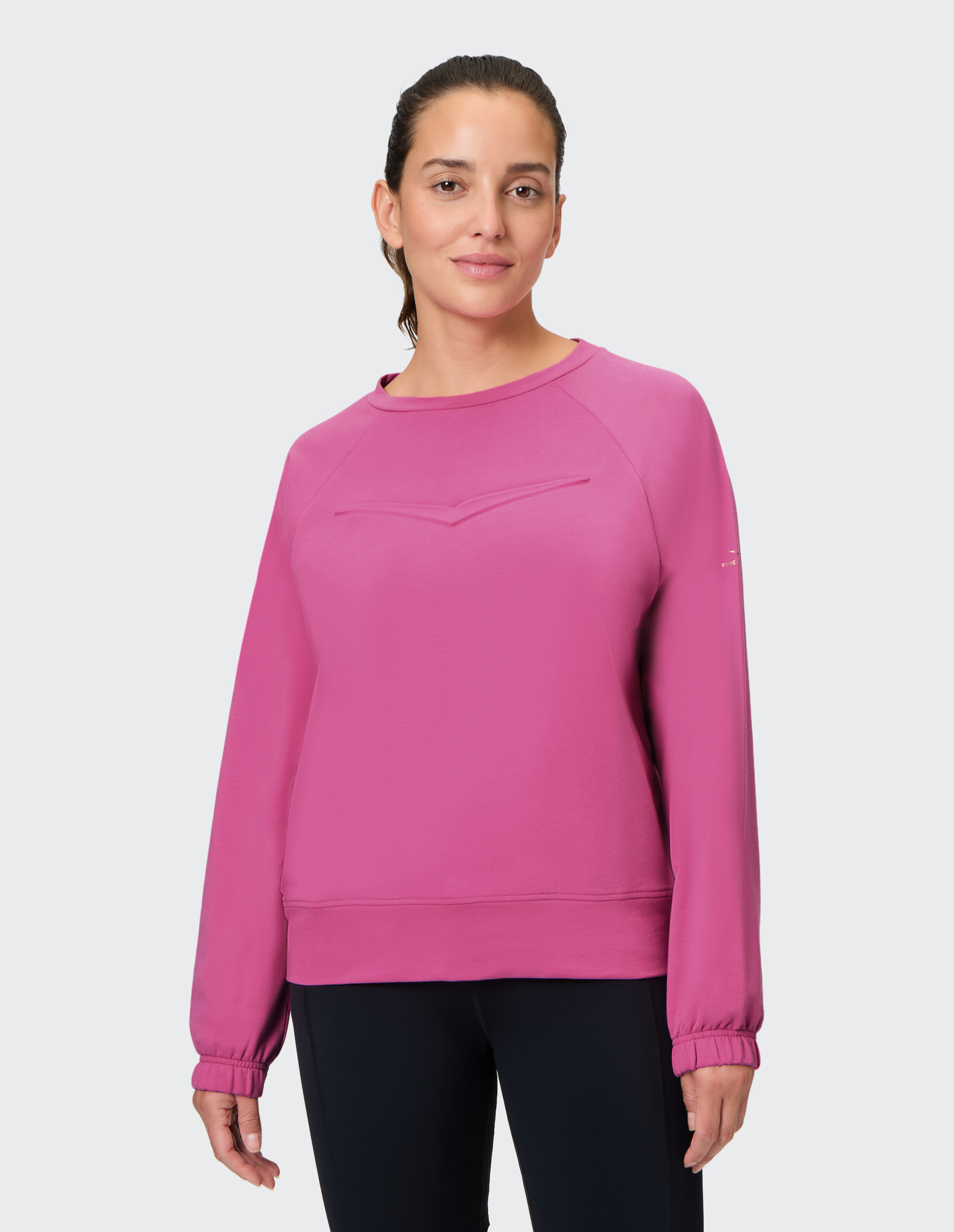 Frau trägt ein gemütliches, rosafarbenes, langärmliges, lässiges Sweatshirt mit Rundhalsausschnitt.