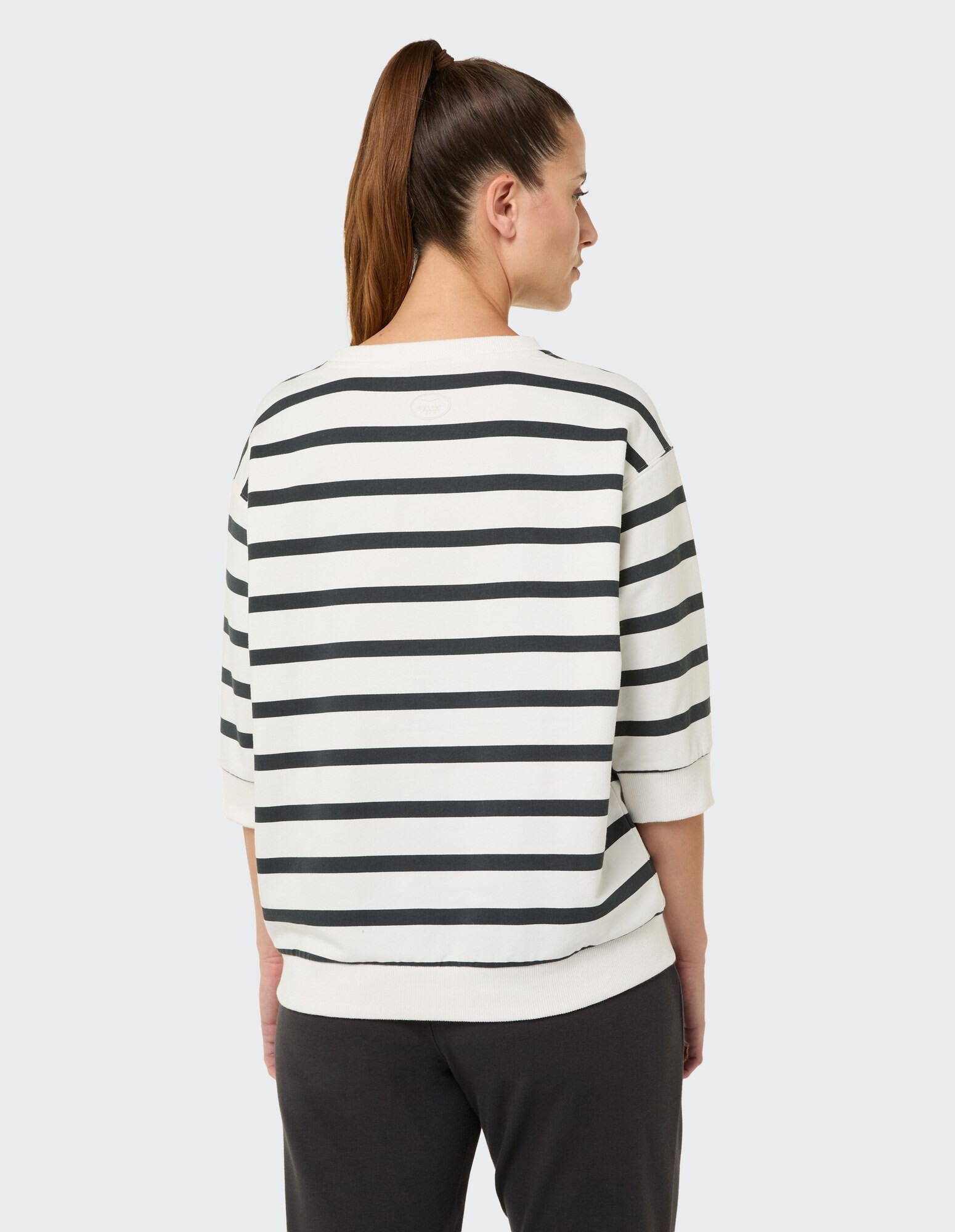 Rückansicht einer Frau in einem gestreiften Freizeit-Sweatshirt, perfekt zum Entspannen.
