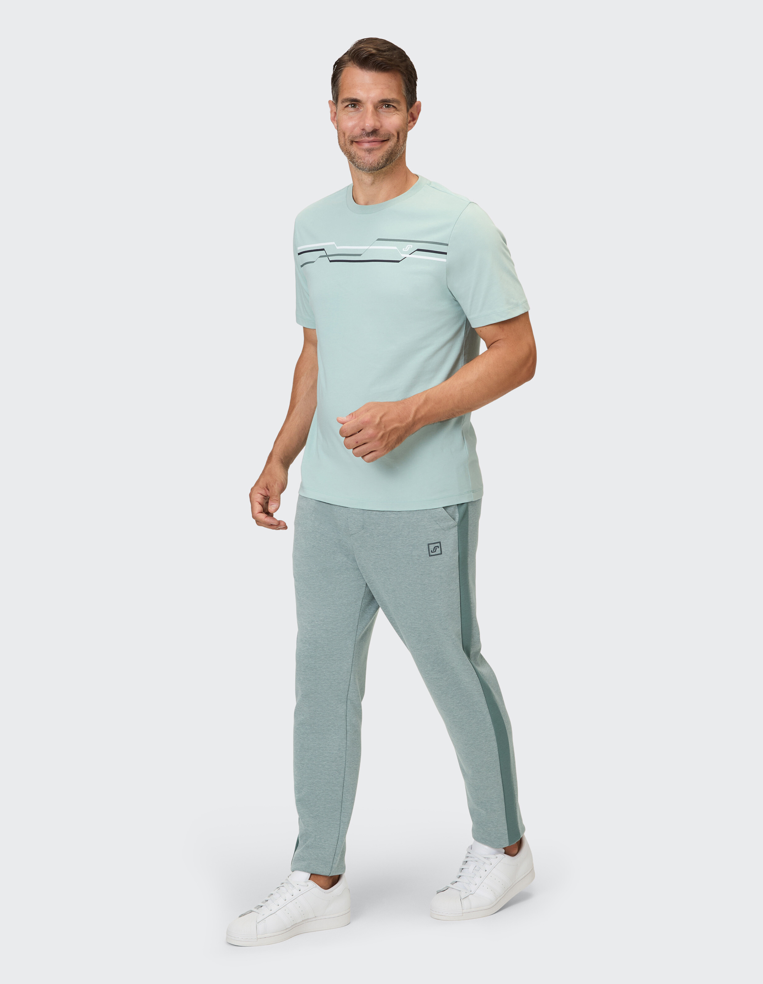 Mann trägt ein mintgrünes Freizeit-T-Shirt und passende Jogginghosen, stilvoll und bequem.