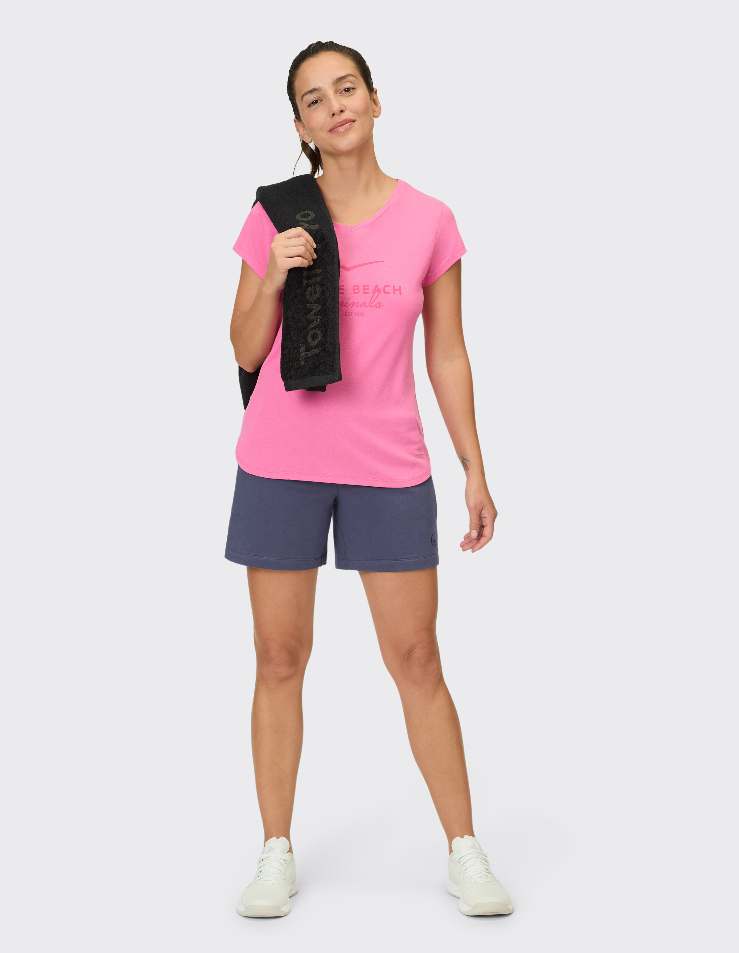 Frau in einem rosafarbenen Grafik-T-Shirt und blauen Shorts zum lässigen Sommer-Lounge.