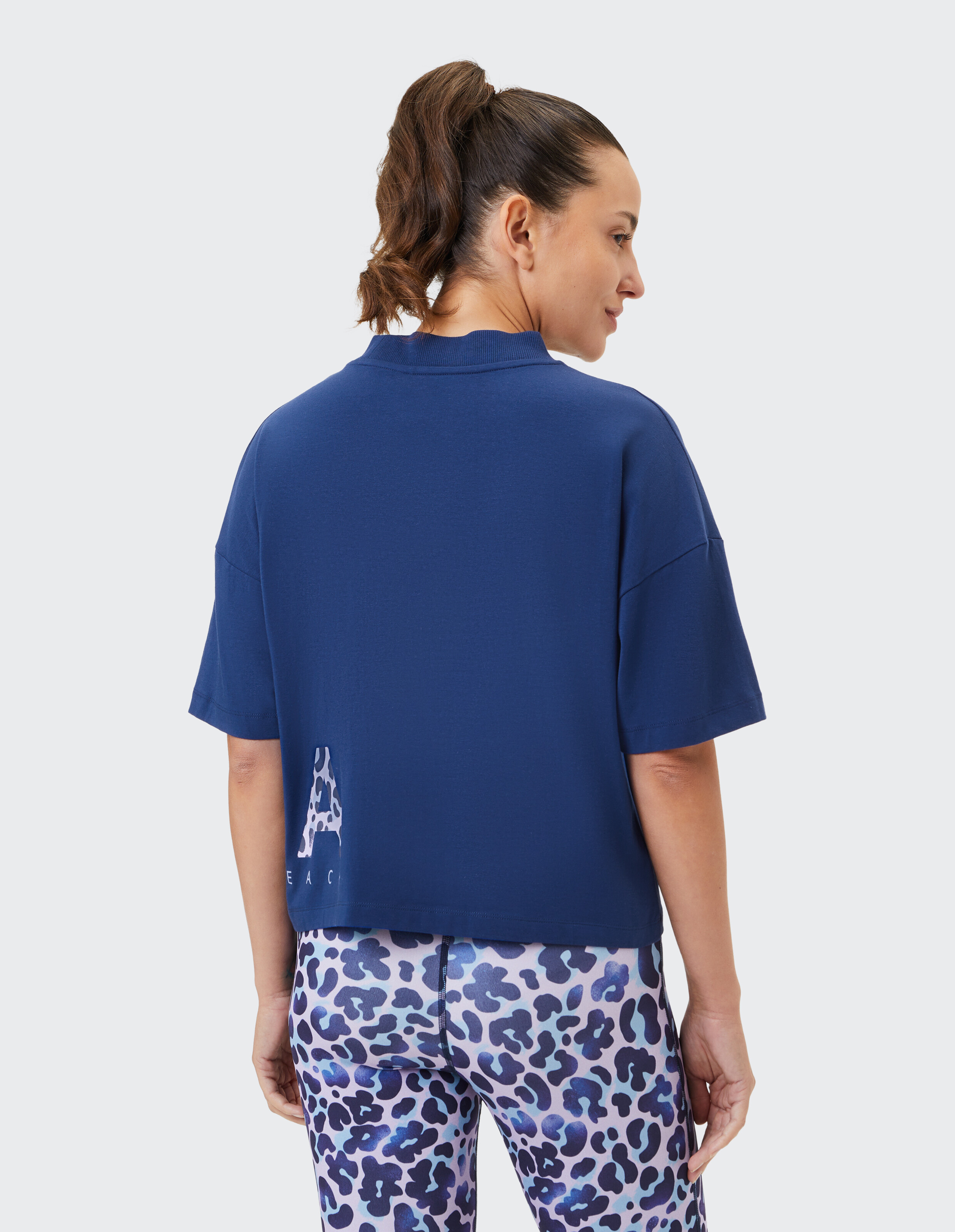 Frau trägt ein marineblaues Freizeit-T-Shirt und gemusterte Leggings für einen bequemen Look.