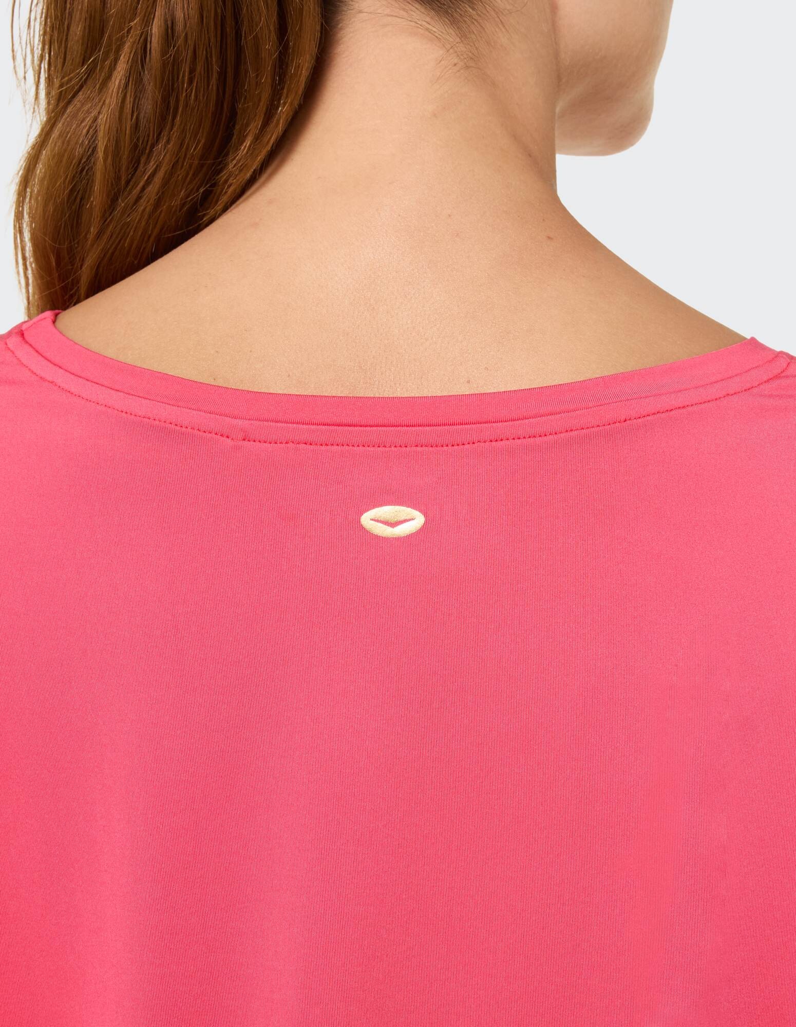 Nahaufnahme der Rückseite eines rosa Freizeitoberteils mit einzigartigem Logodetail.