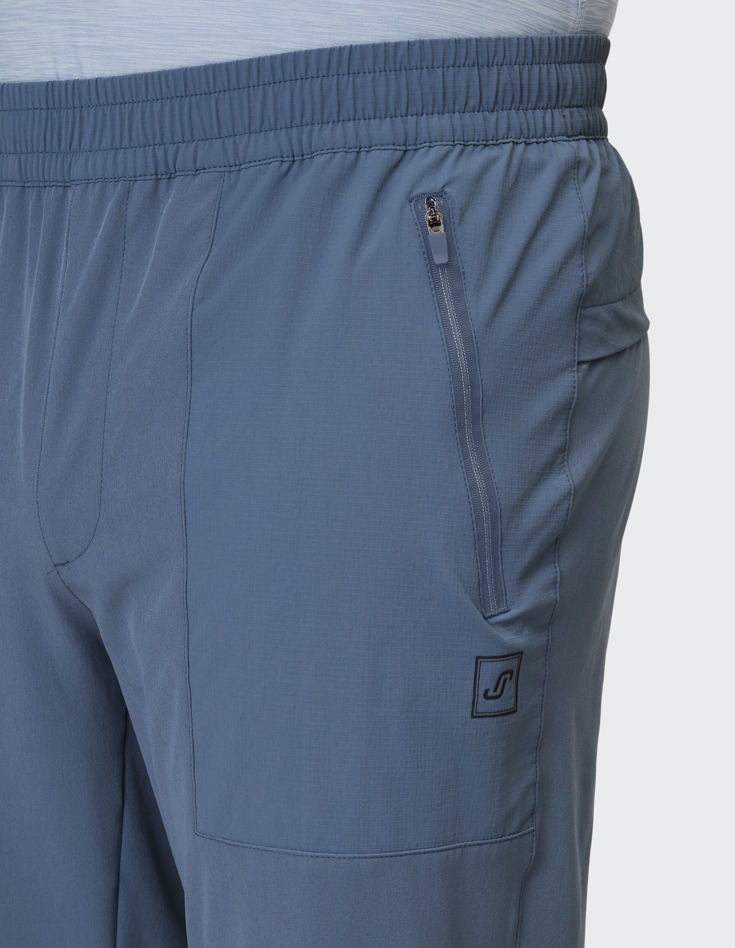 Nahaufnahme einer blauen Freizeithose mit elastischem Bund und Reißverschlusstasche.