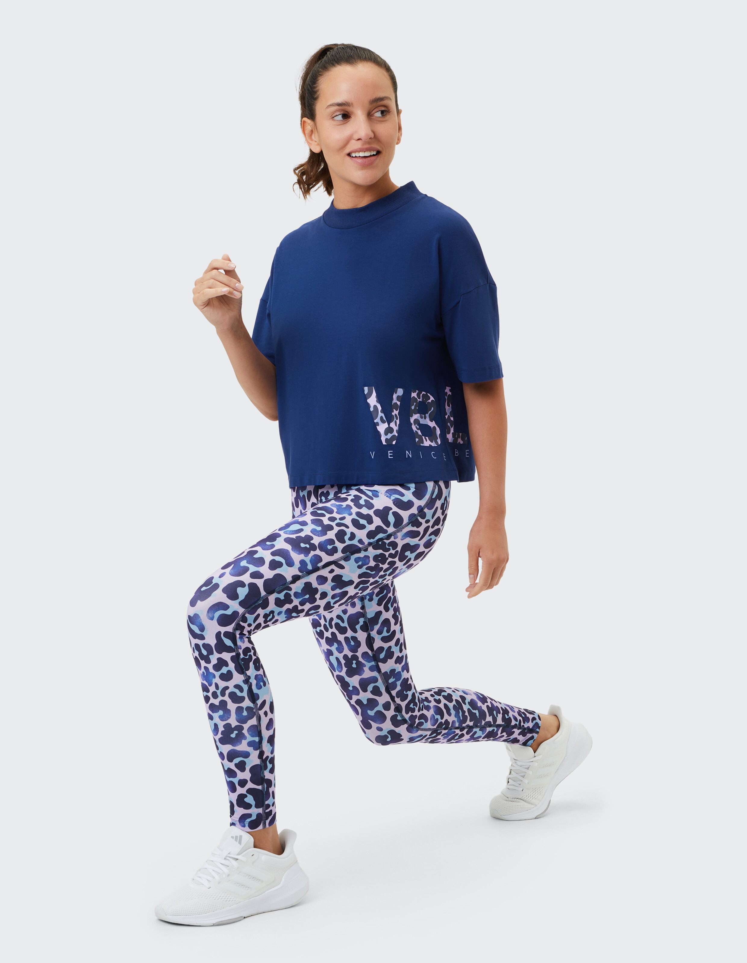 Frau trägt ein marineblaues, kastenförmiges T-Shirt und blaue Leggings mit Leopardenmuster für einen lässigen Stil.