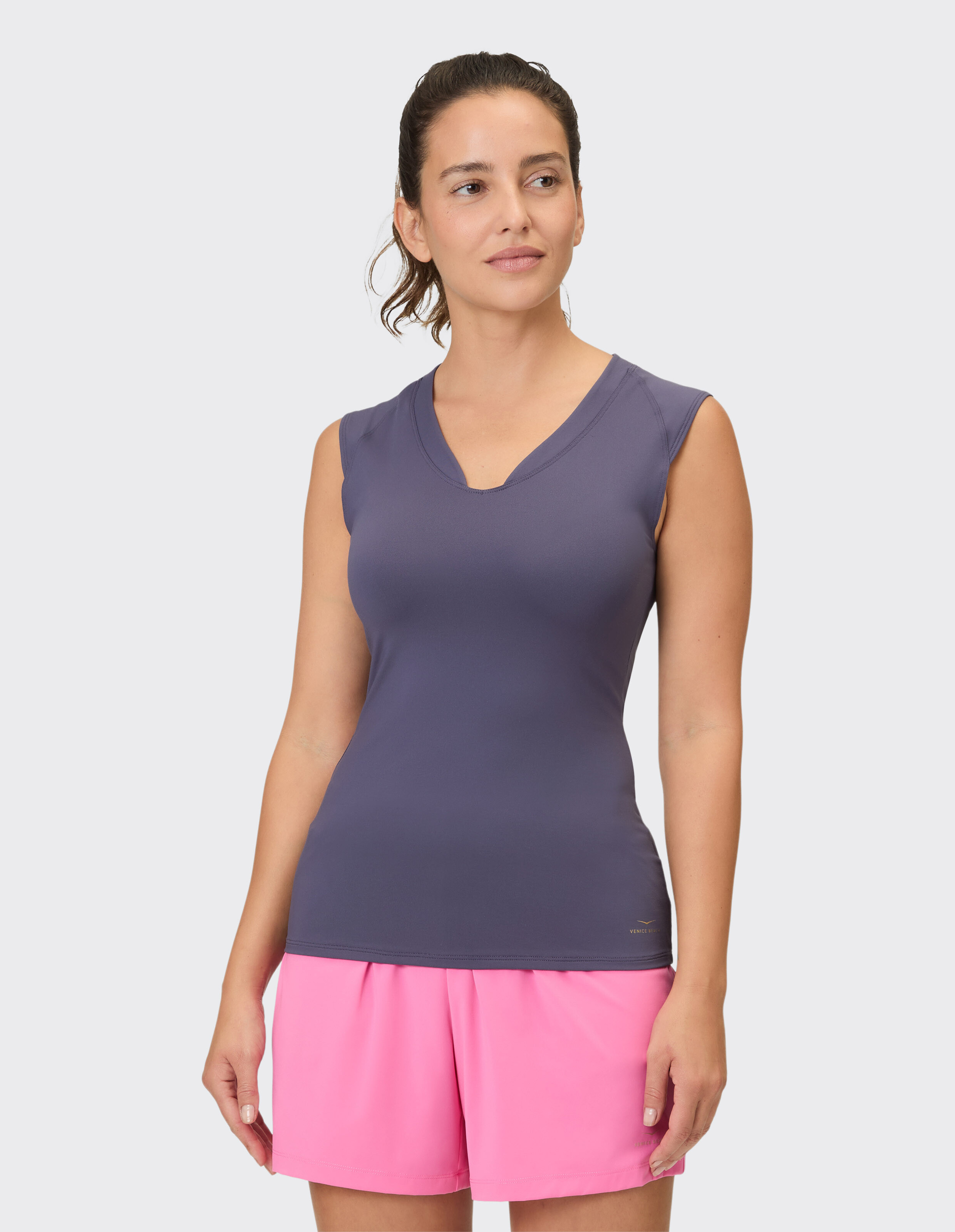 Frau trägt ein ärmelloses dunkelviolettes Oberteil und rosa Shorts, ideal für Freizeitausflüge oder Workouts.