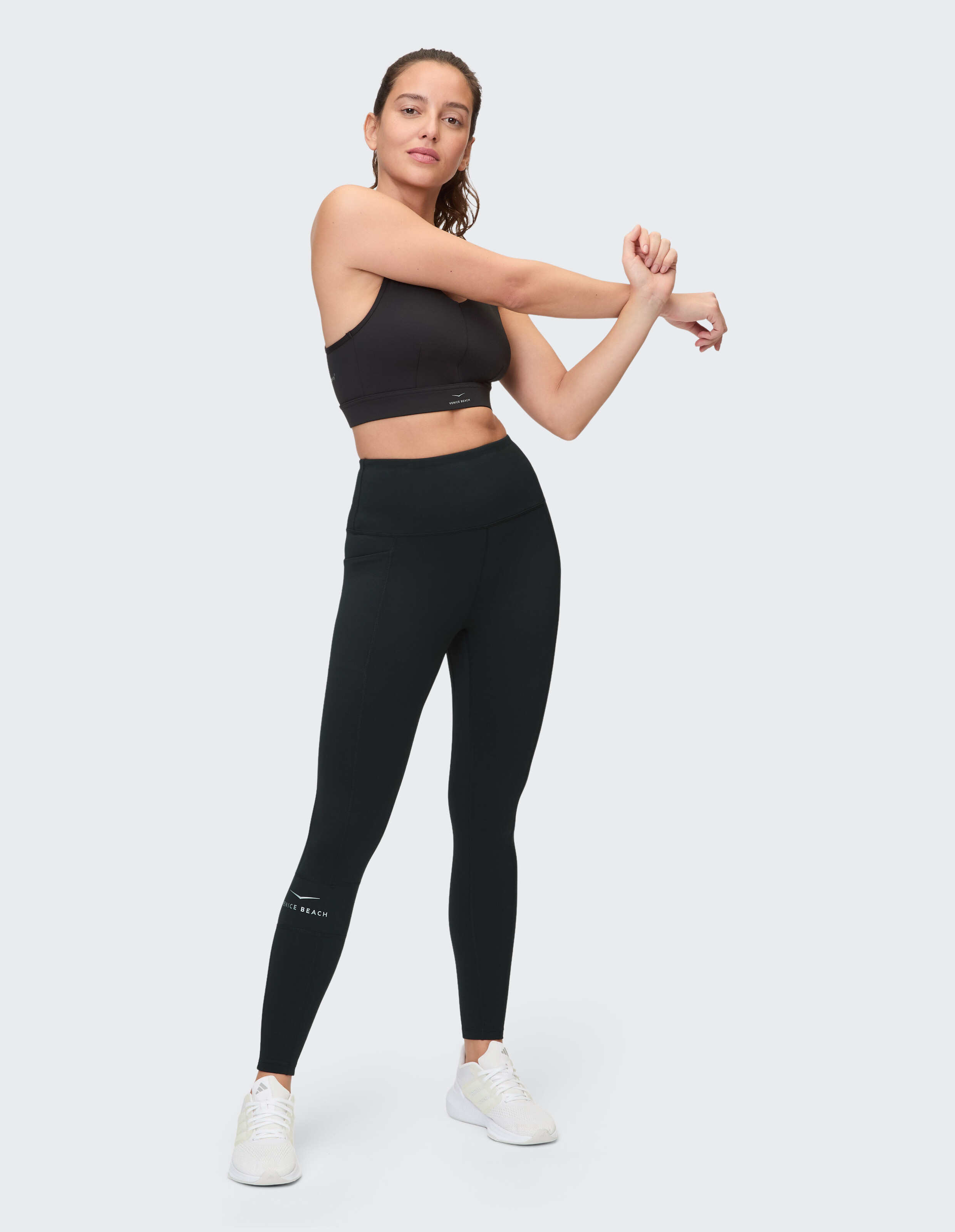 Model in schwarzem Sport-BH und Leggings, im lässigen Activewear-Stil.