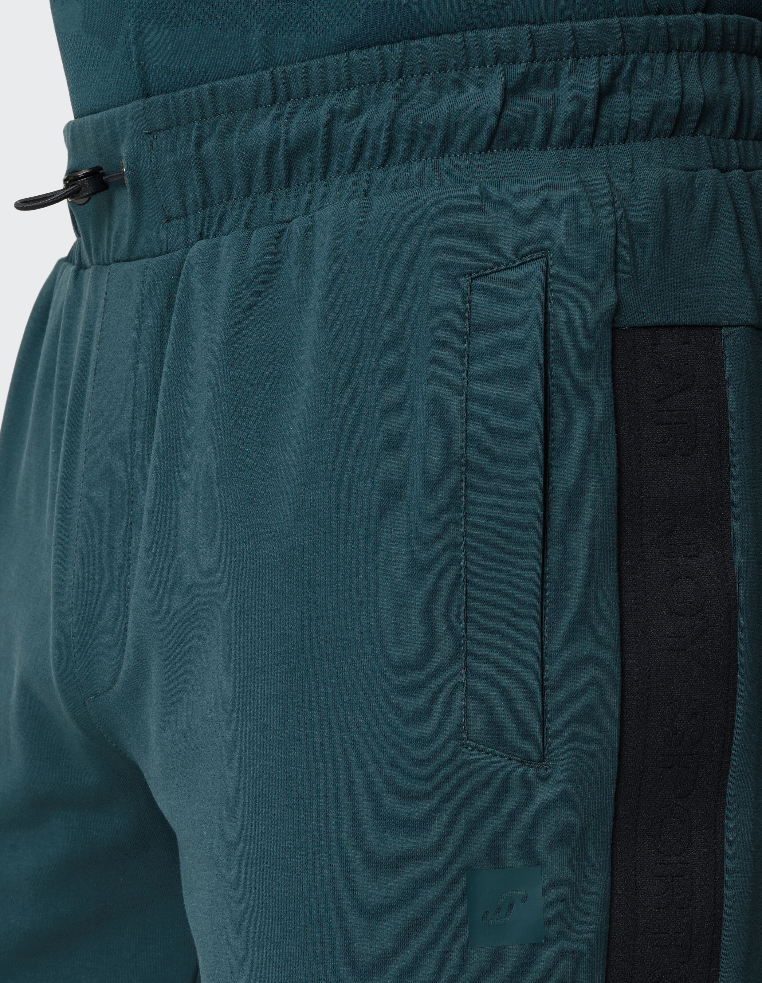 Nahaufnahme einer blaugrünen Jogginghose mit elastischem Bund und Seitentasche.