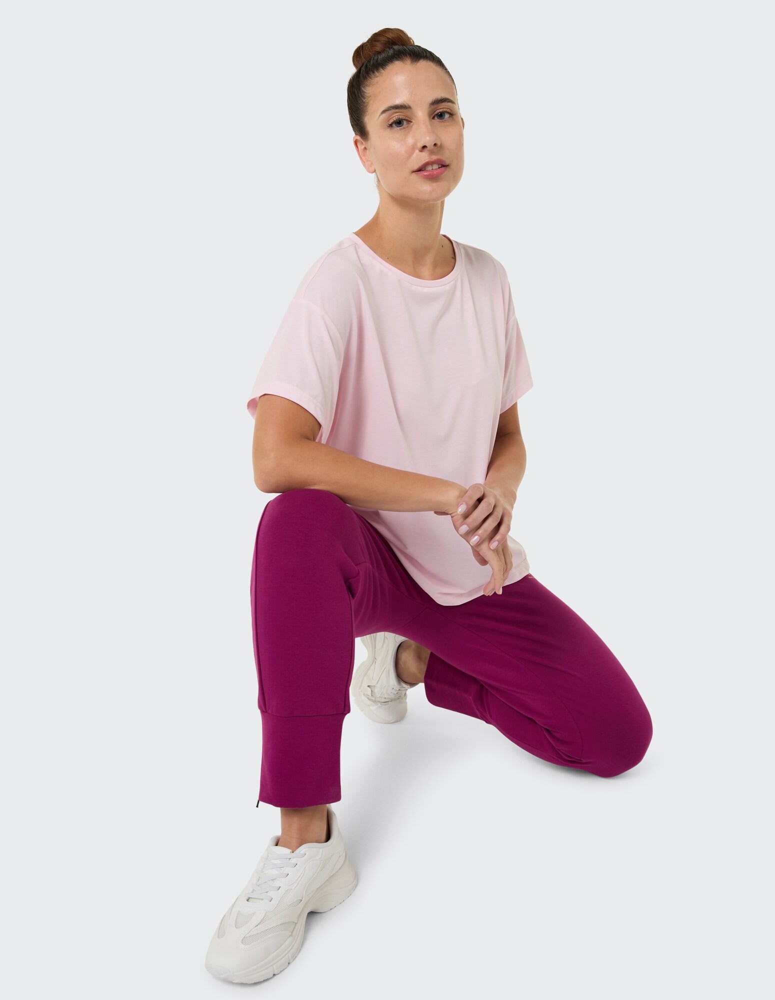 Frau in rosa T-Shirt und lila Jogginghose, lässig gestylt.