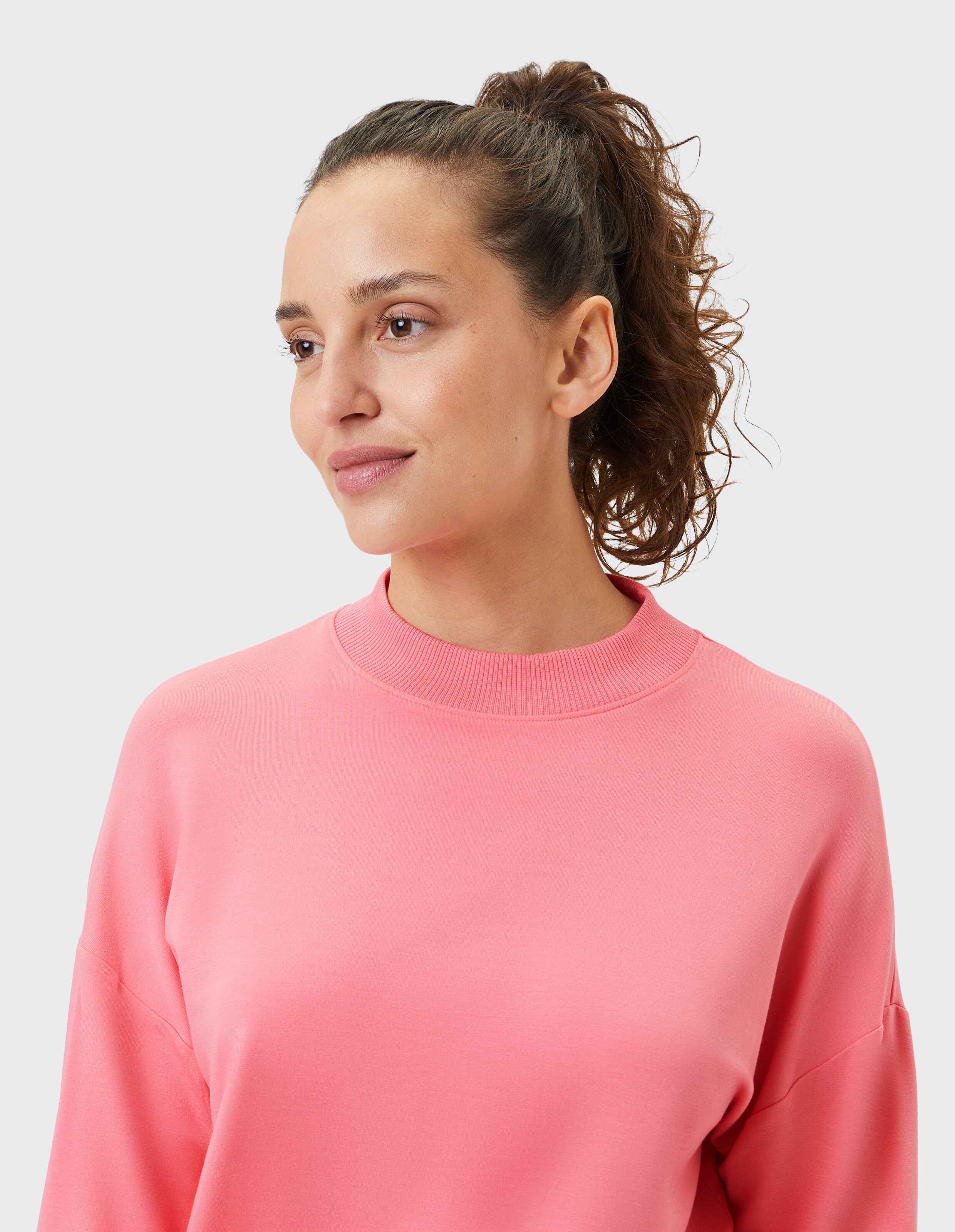 Frau trägt ein kuscheliges rosa Sweatshirt mit Stehkragen zum entspannten Faulenzen.