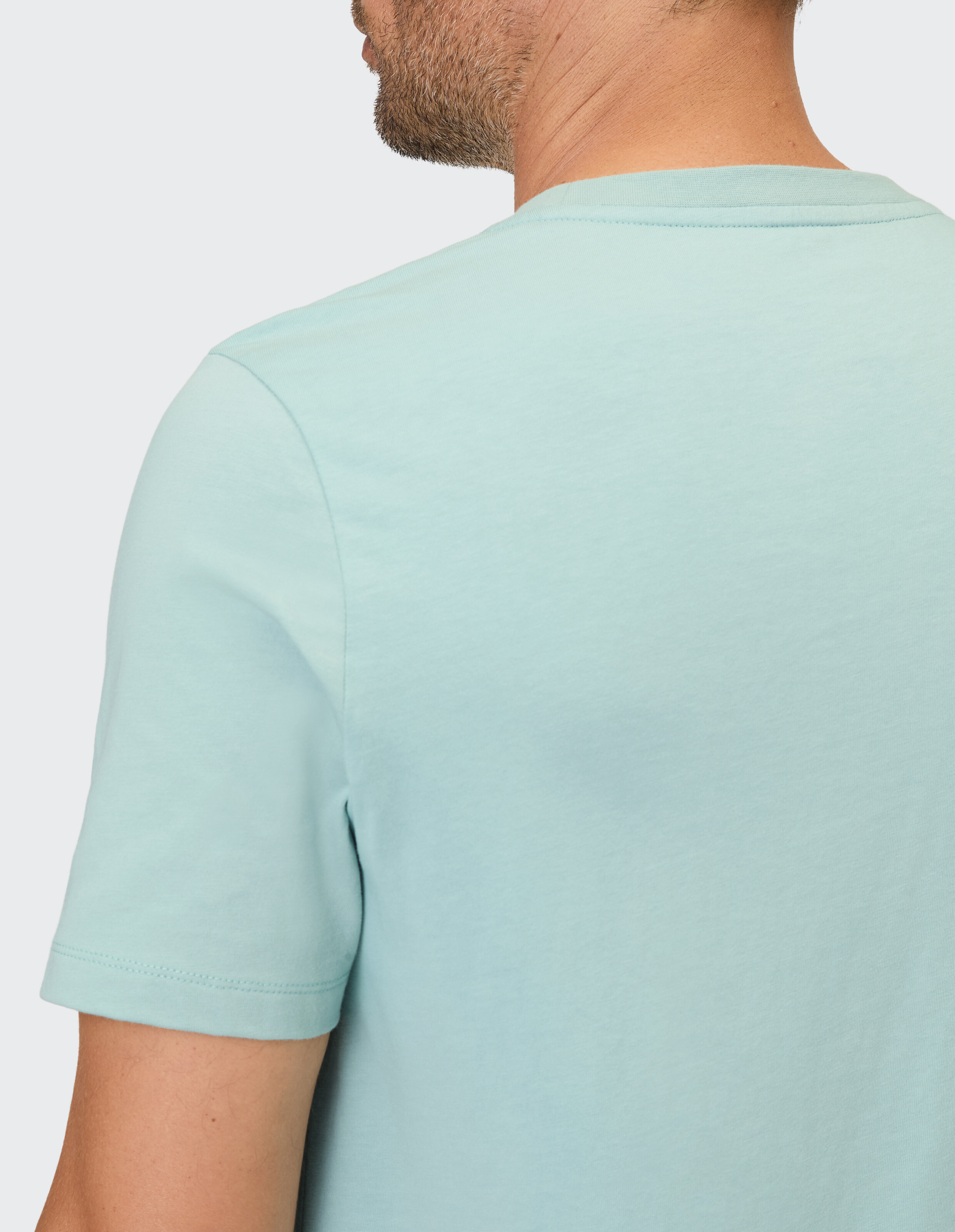 Ein Mann trägt ein hellblaues, kurzärmeliges T-Shirt mit rundem Ausschnitt.