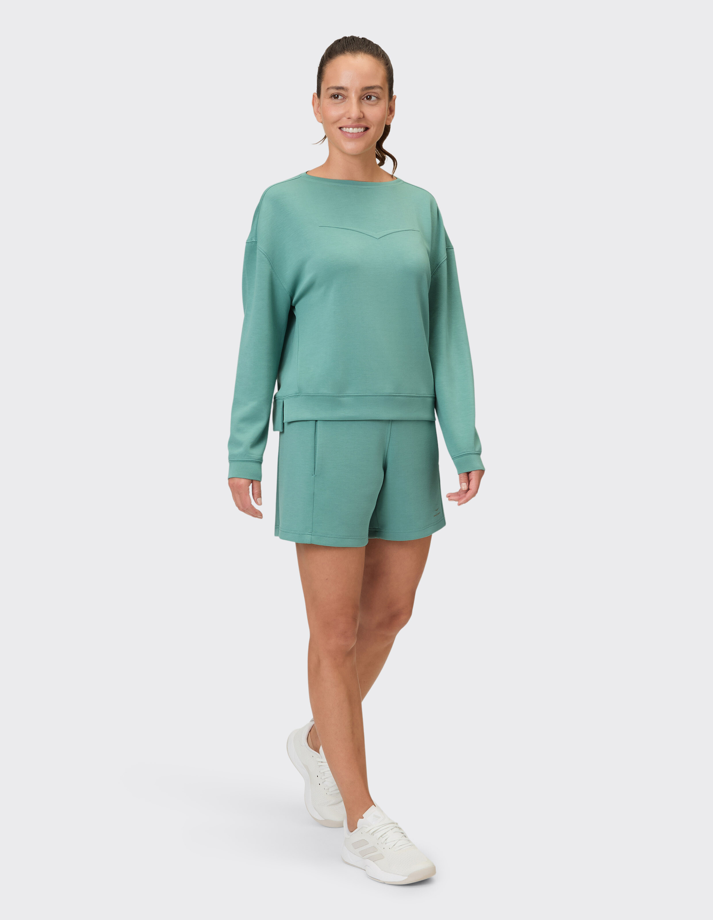 Frau trägt Hayley-Shorts von Venice Beach und ein passendes grünes Sweatshirt für Freizeitkleidung.