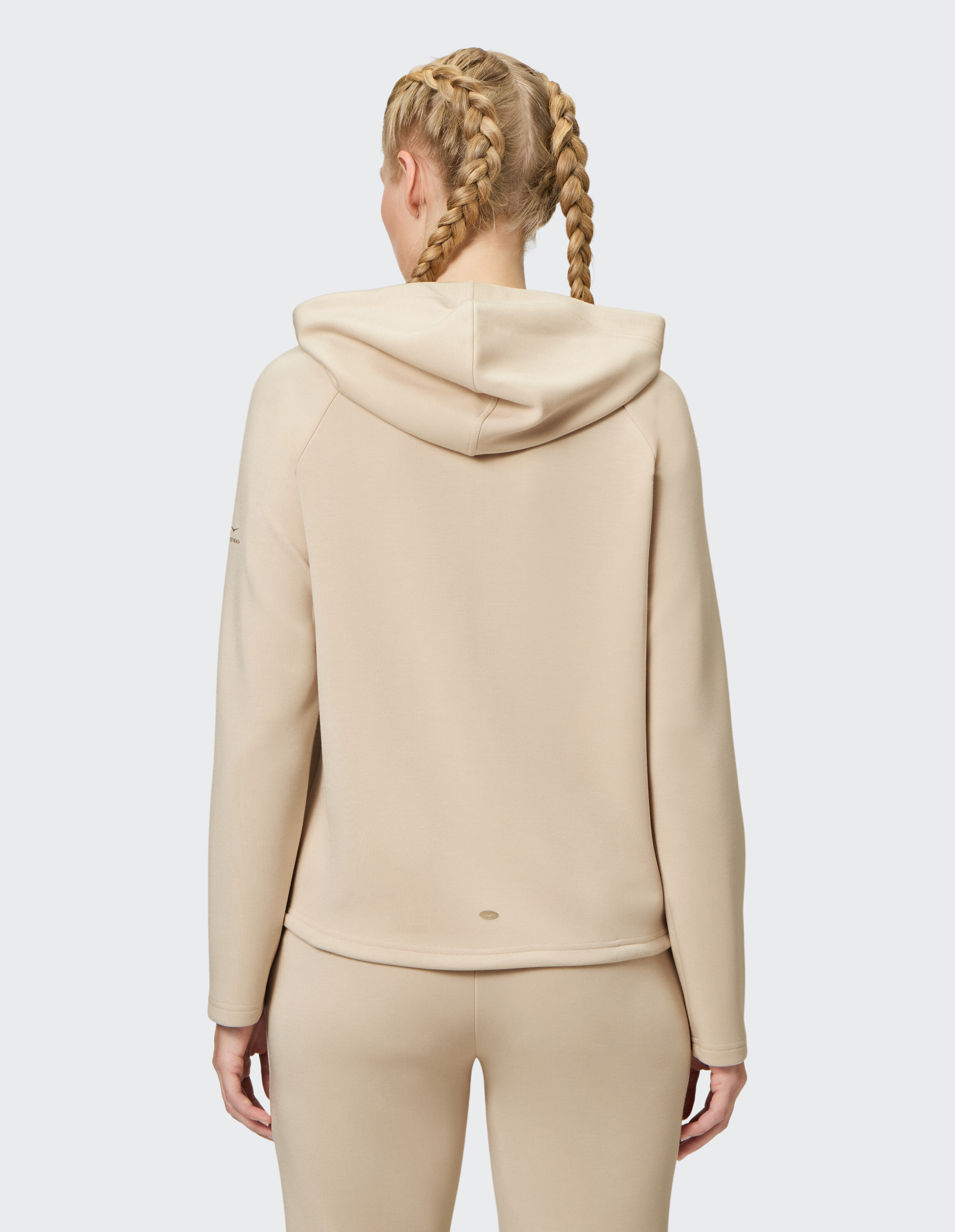 Frau trägt einen kuscheligen beigen ELBSAND-Hoodie für lässige Loungewear, Rückansicht.