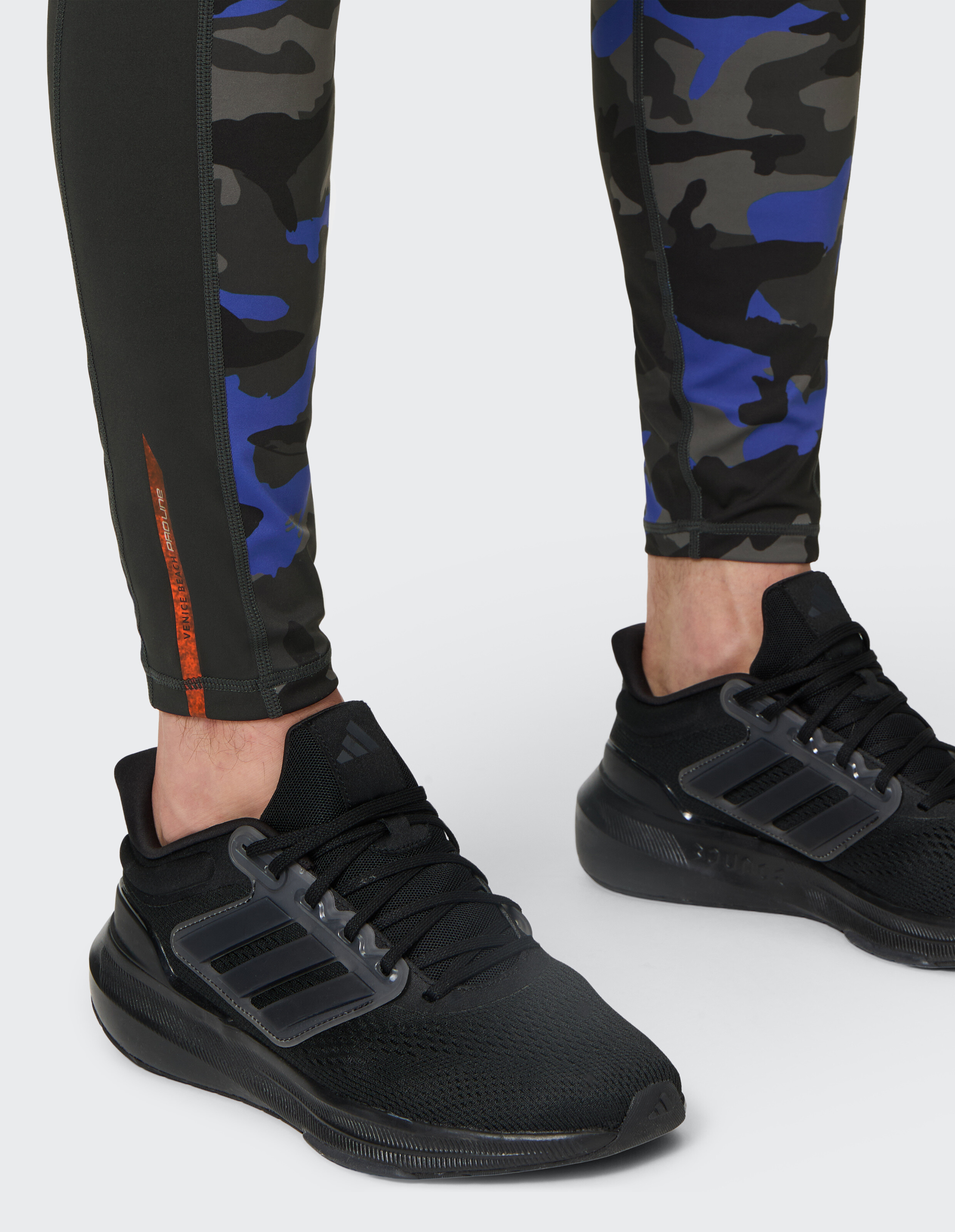 Person trägt blaue und graue Camouflage-Leggings und schwarze Sportschuhe.