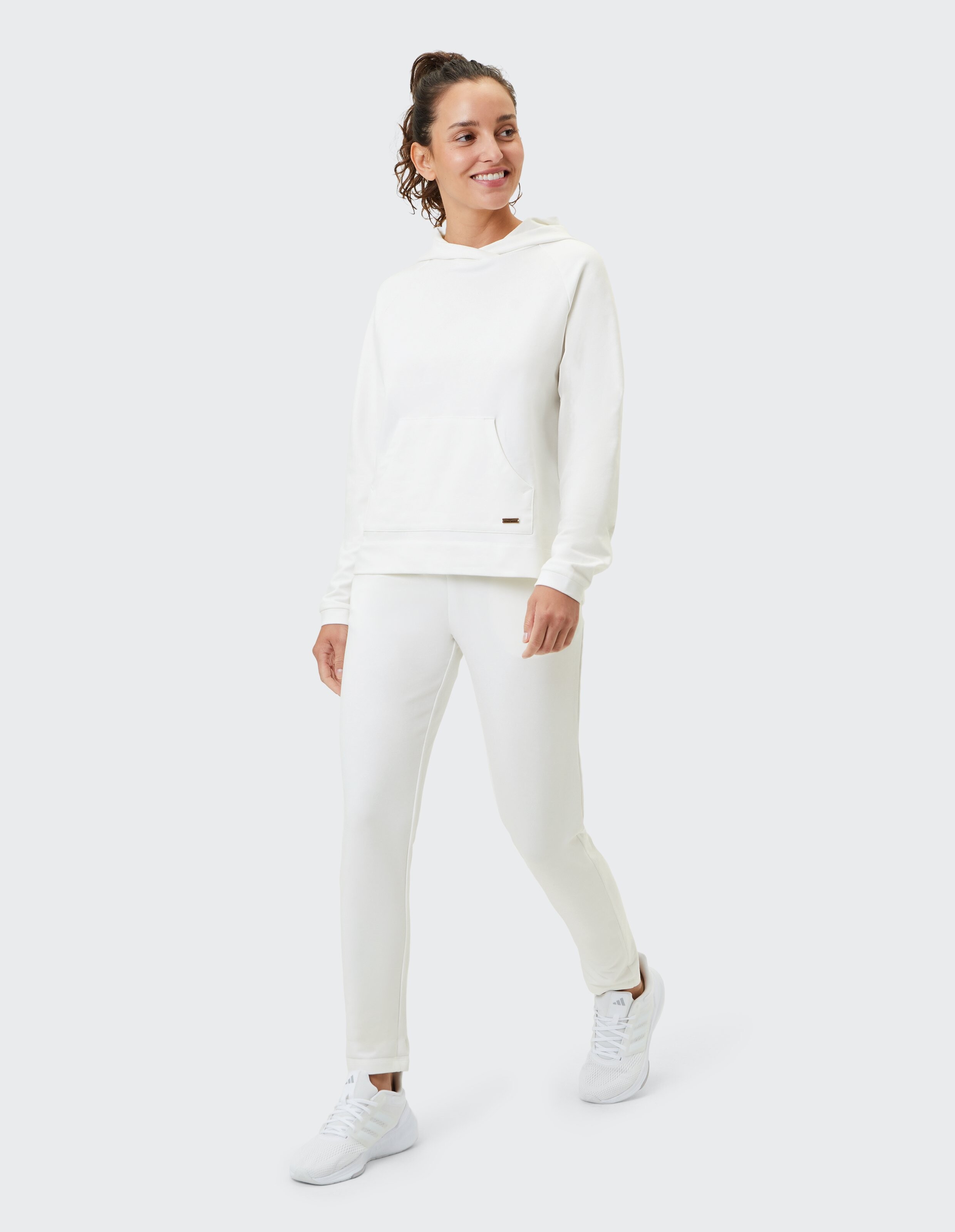 Frau in einem gemütlichen weißen Kapuzenpullover und passenden Jogginghosen, perfekt für Freizeitkleidung.