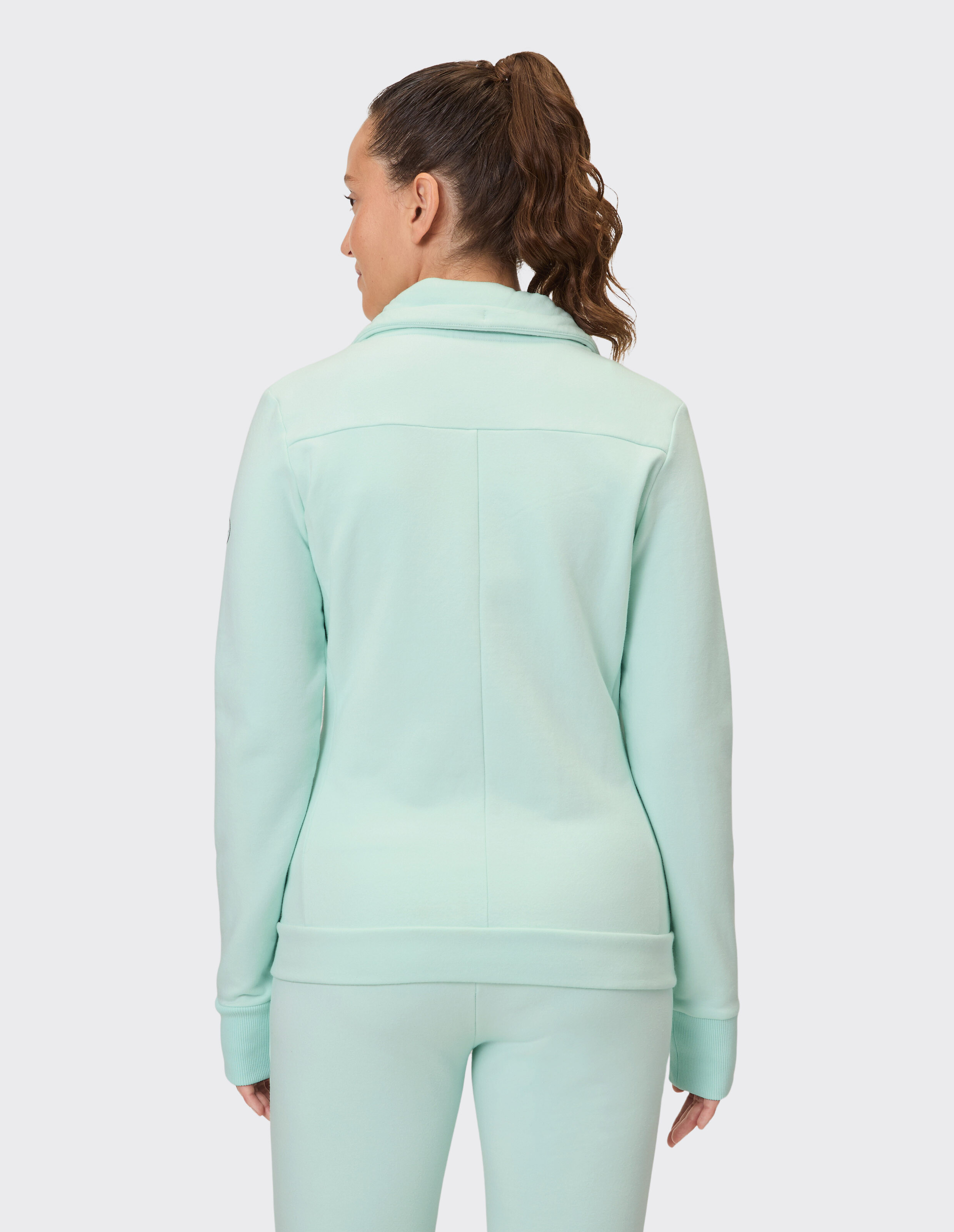 Rückansicht einer Frau in einer mintgrünen Freizeitjacke, perfekt zum Entspannen.