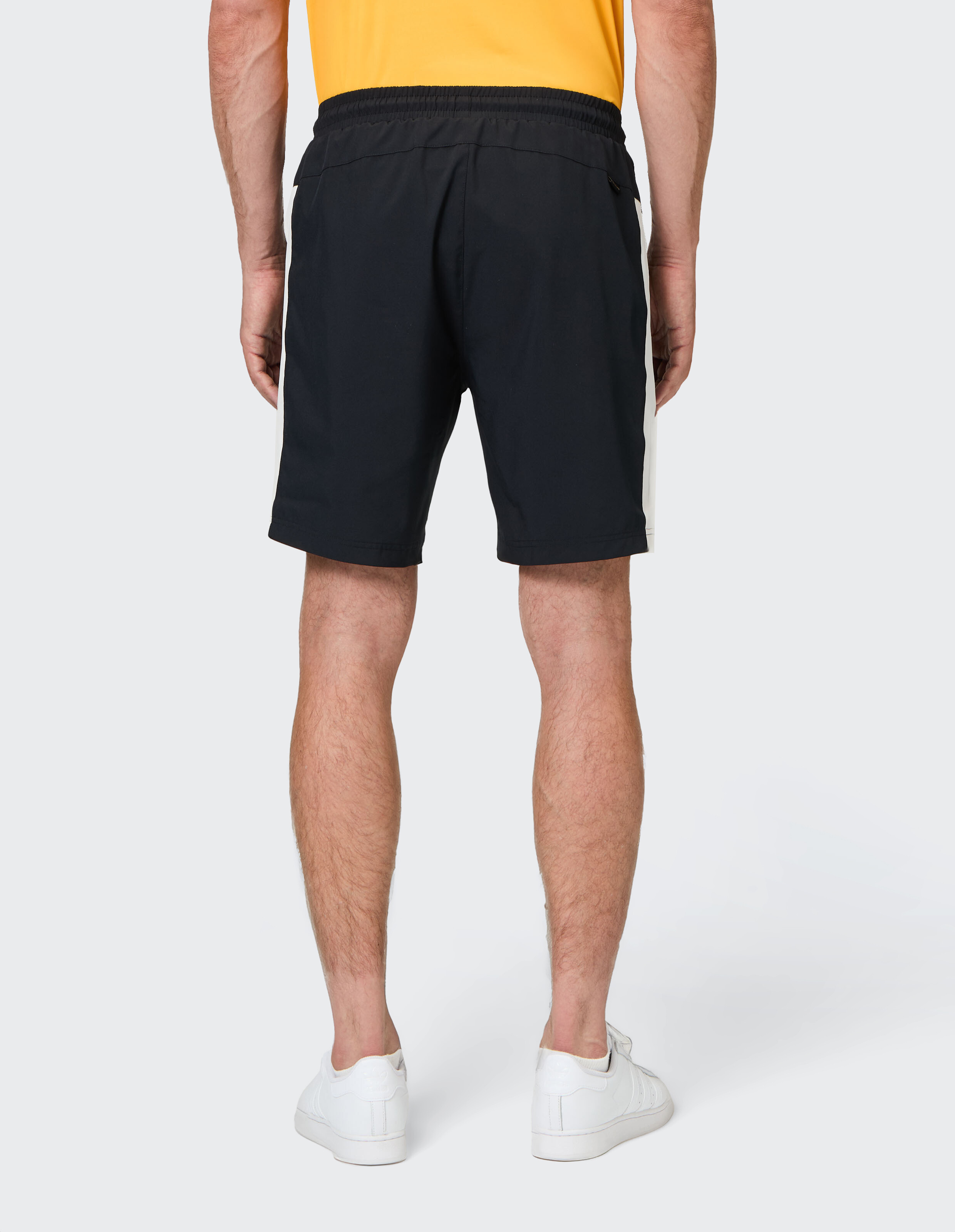 Rückansicht eines Mannes, der schwarze Freizeitshorts mit weißen Seitenstreifen trägt.