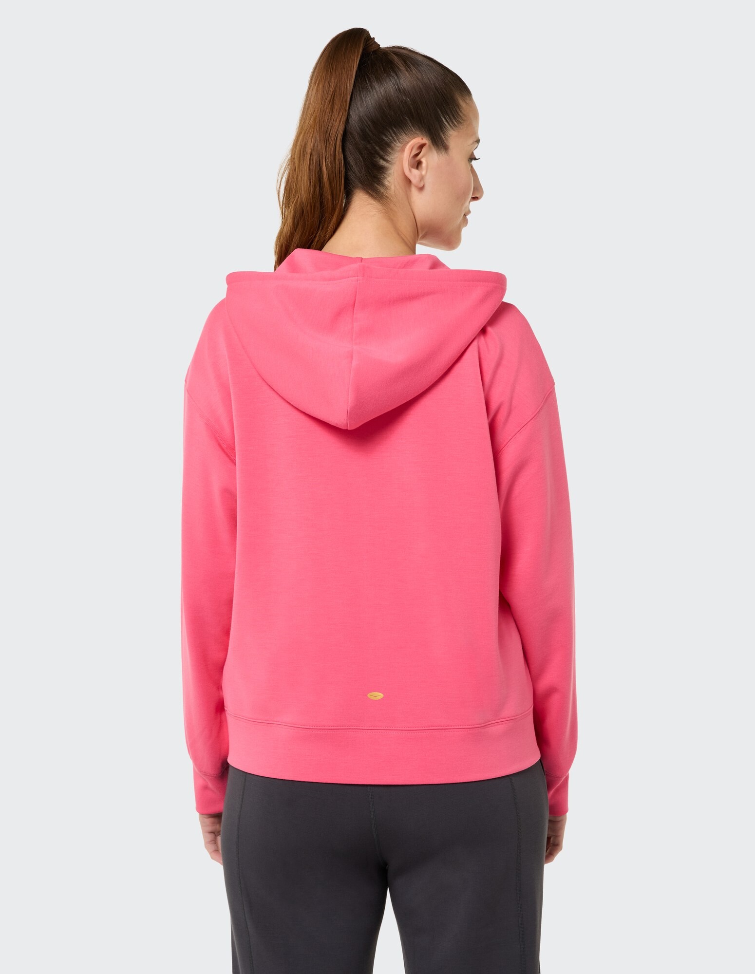 Rückansicht einer Frau in einem rosa Kapuzenpullover, perfekt für Freizeitkleidung und Faulenzen.
