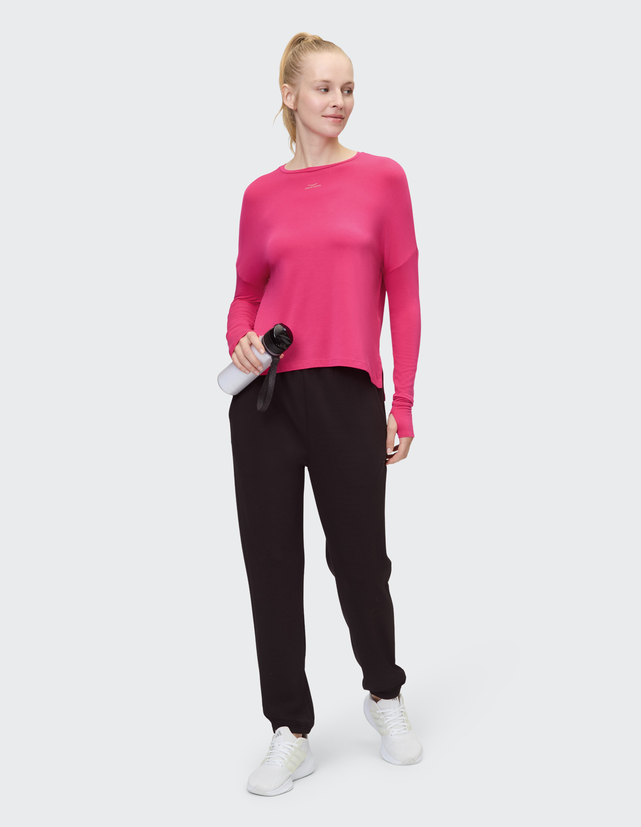 Frau trägt ein rosa Langarmhemd und eine schwarze Jogginghose für einen gemütlichen, lässigen Look.