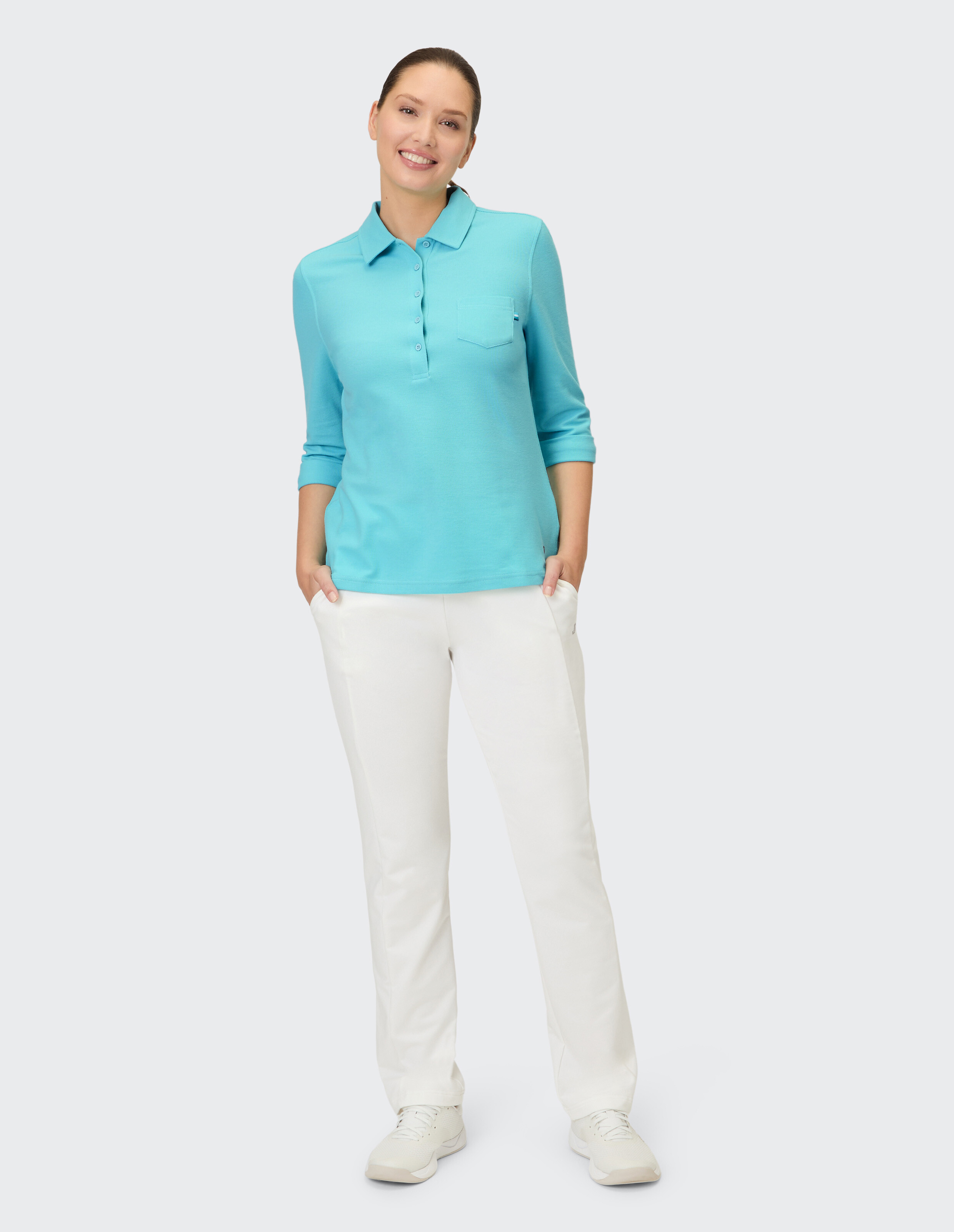 Frau in einem hellblauen Poloshirt und einer weißen Hose, die einen lässigen Stil zur Schau stellt.