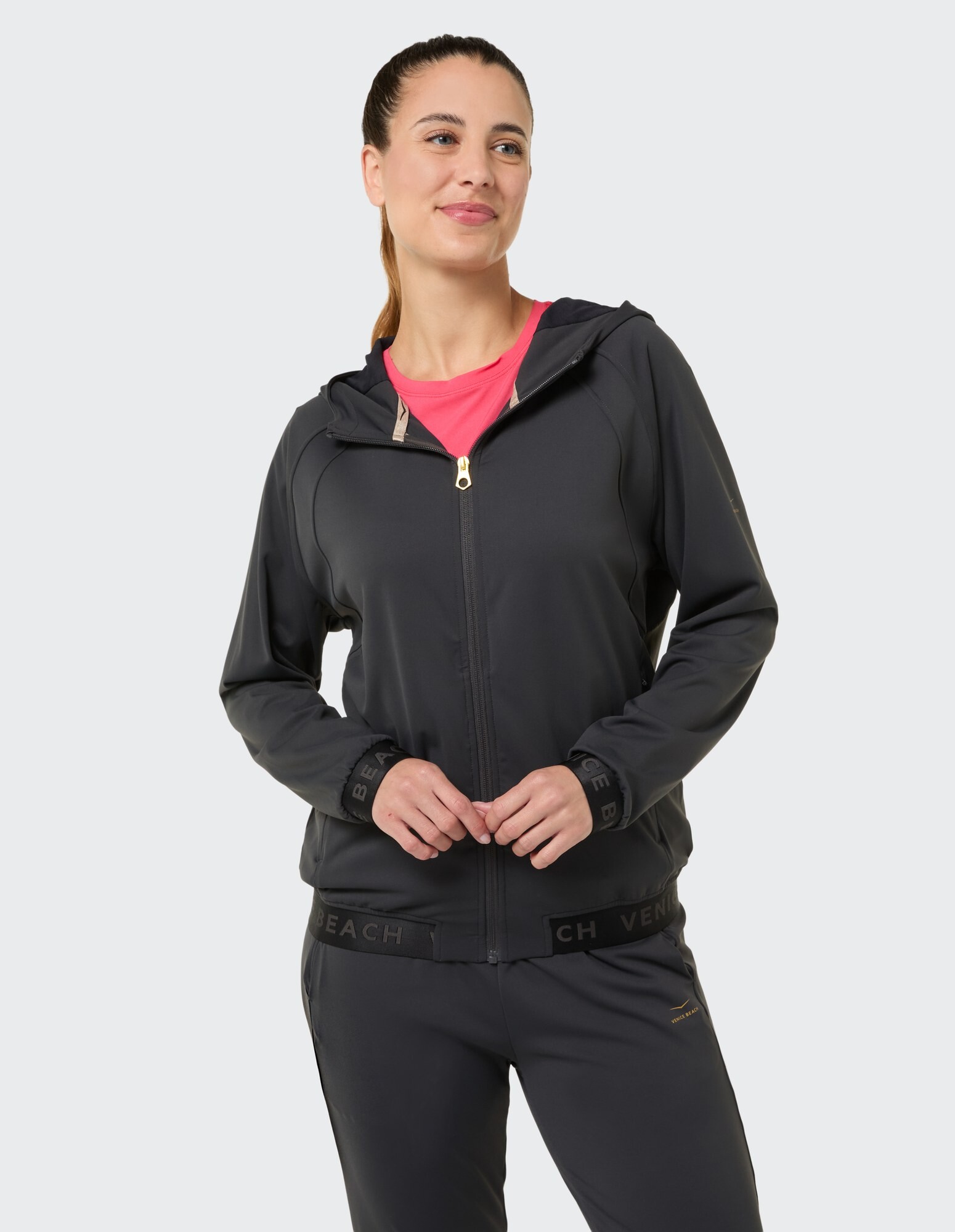 Frau in einer stilvollen schwarzen Jacke mit Reißverschluss und rosa Oberteil, perfekt für Freizeitausflüge.