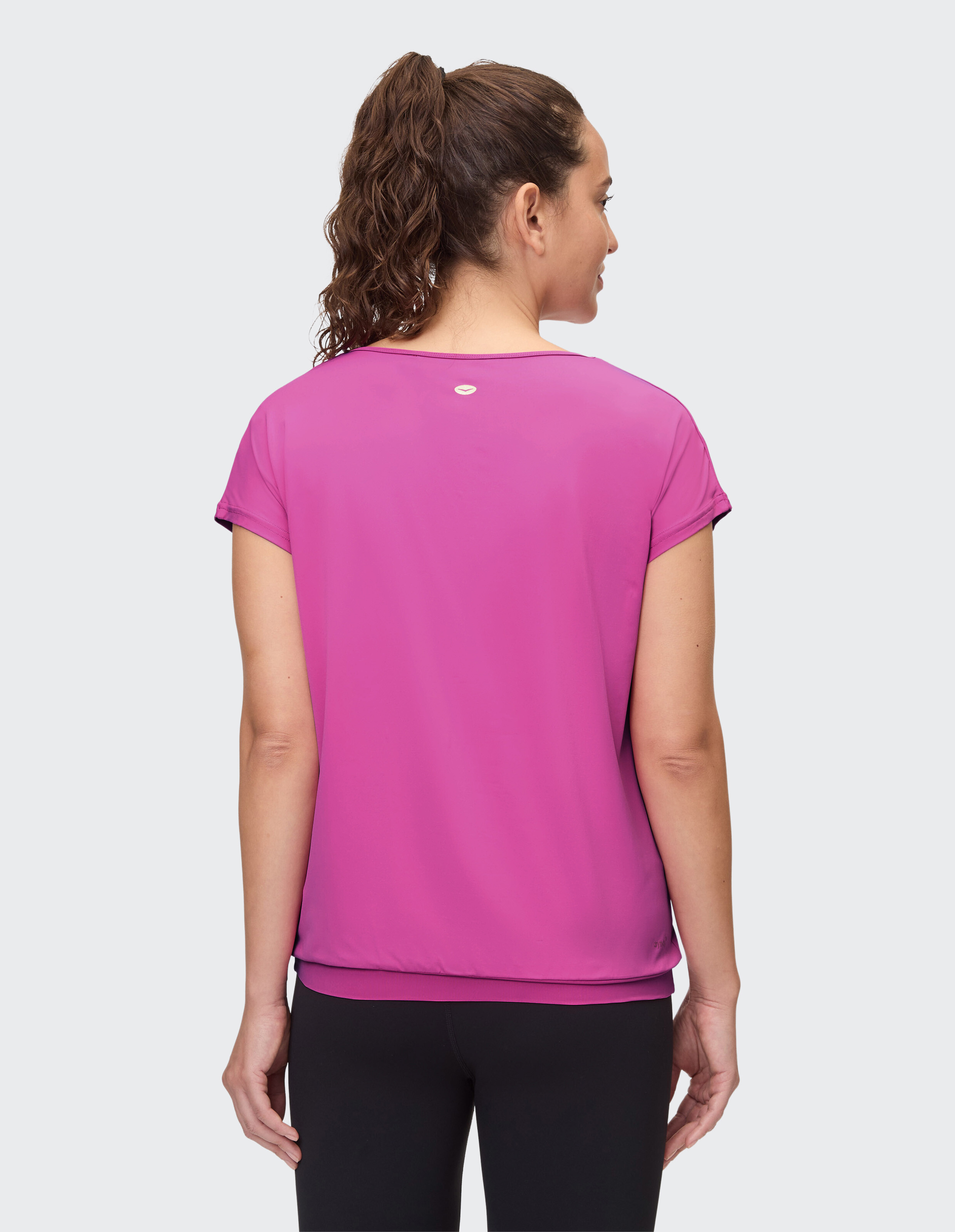 Rückansicht einer Frau in einem leuchtend rosa Kurzarm-Top, perfekt für Freizeitkleidung.
