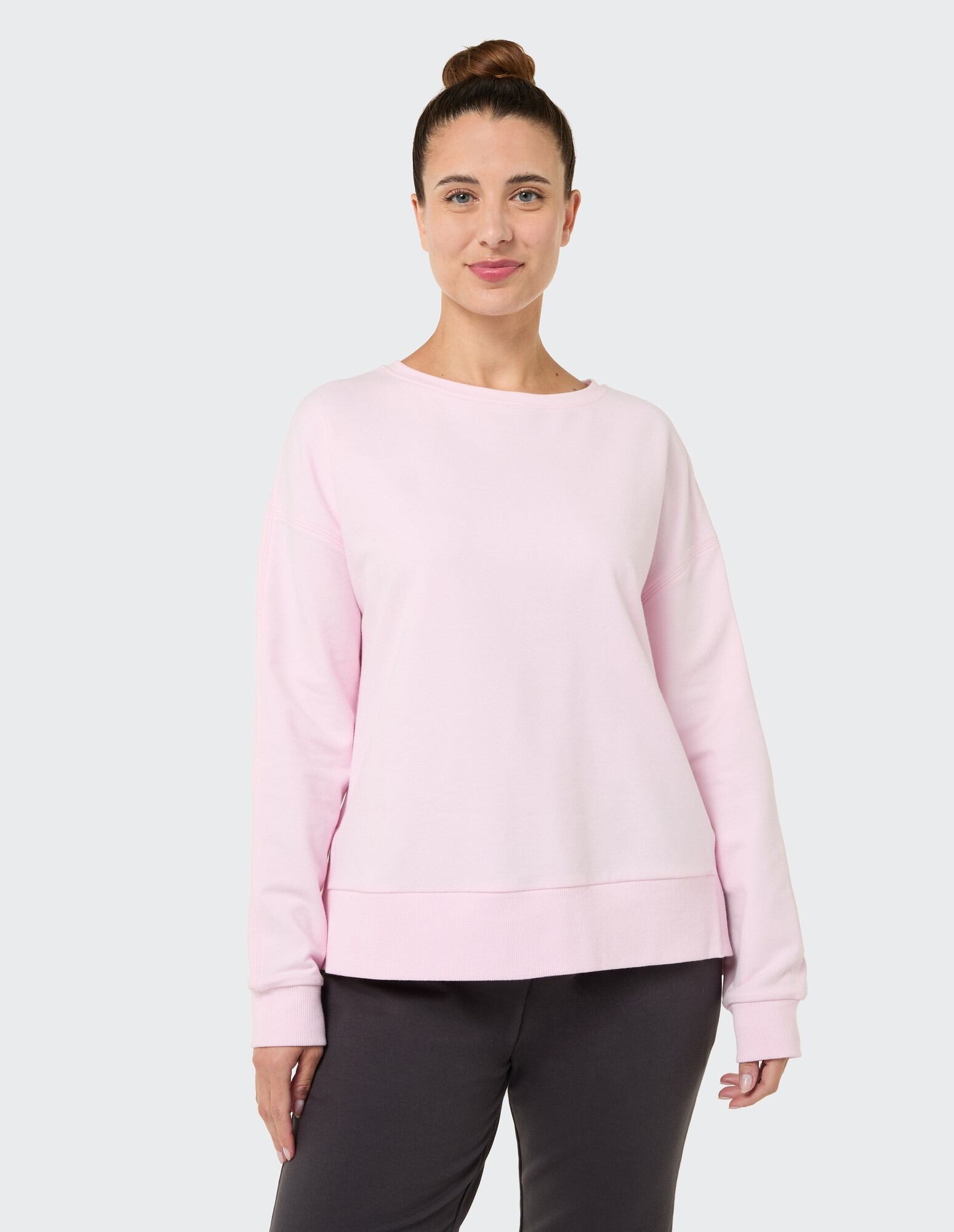 Frau trägt ein kuscheliges rosa Sweatshirt, perfekt zum entspannten Faulenzen oder Brunch.