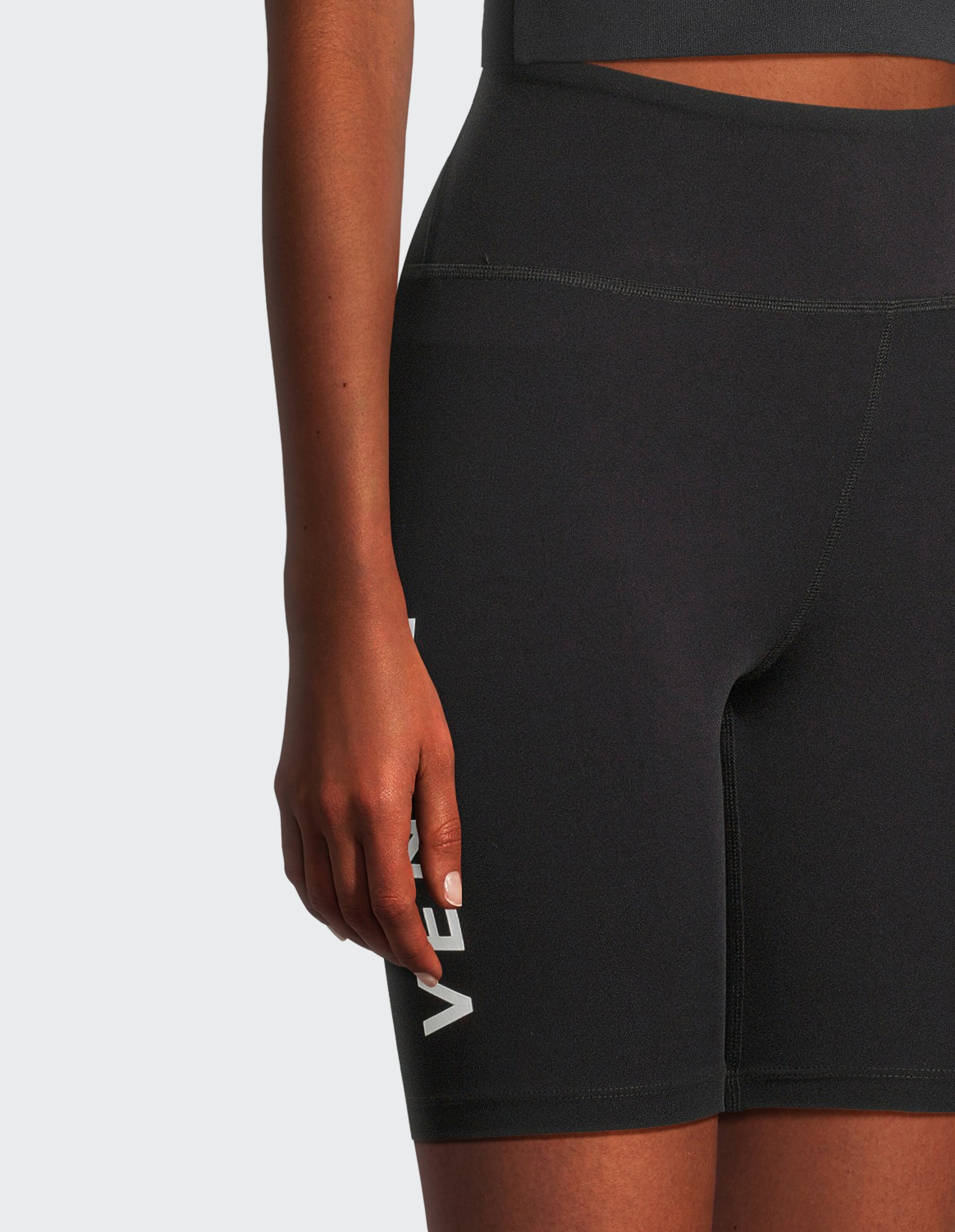 Nahaufnahme einer schwarzen Biker-Shorts mit hoher Taille und weißem Logo-Detail für lässige Lounge-Kleidung.