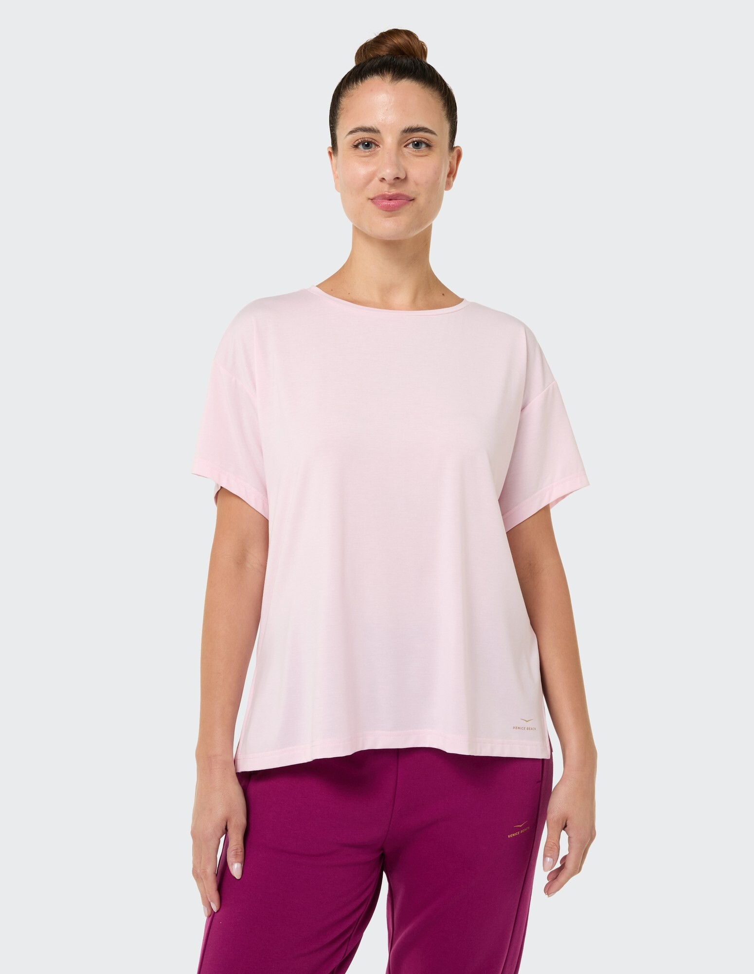 Hellrosa, lässiges T-Shirt mit kurzen Ärmeln, gepaart mit einer lila Hose.