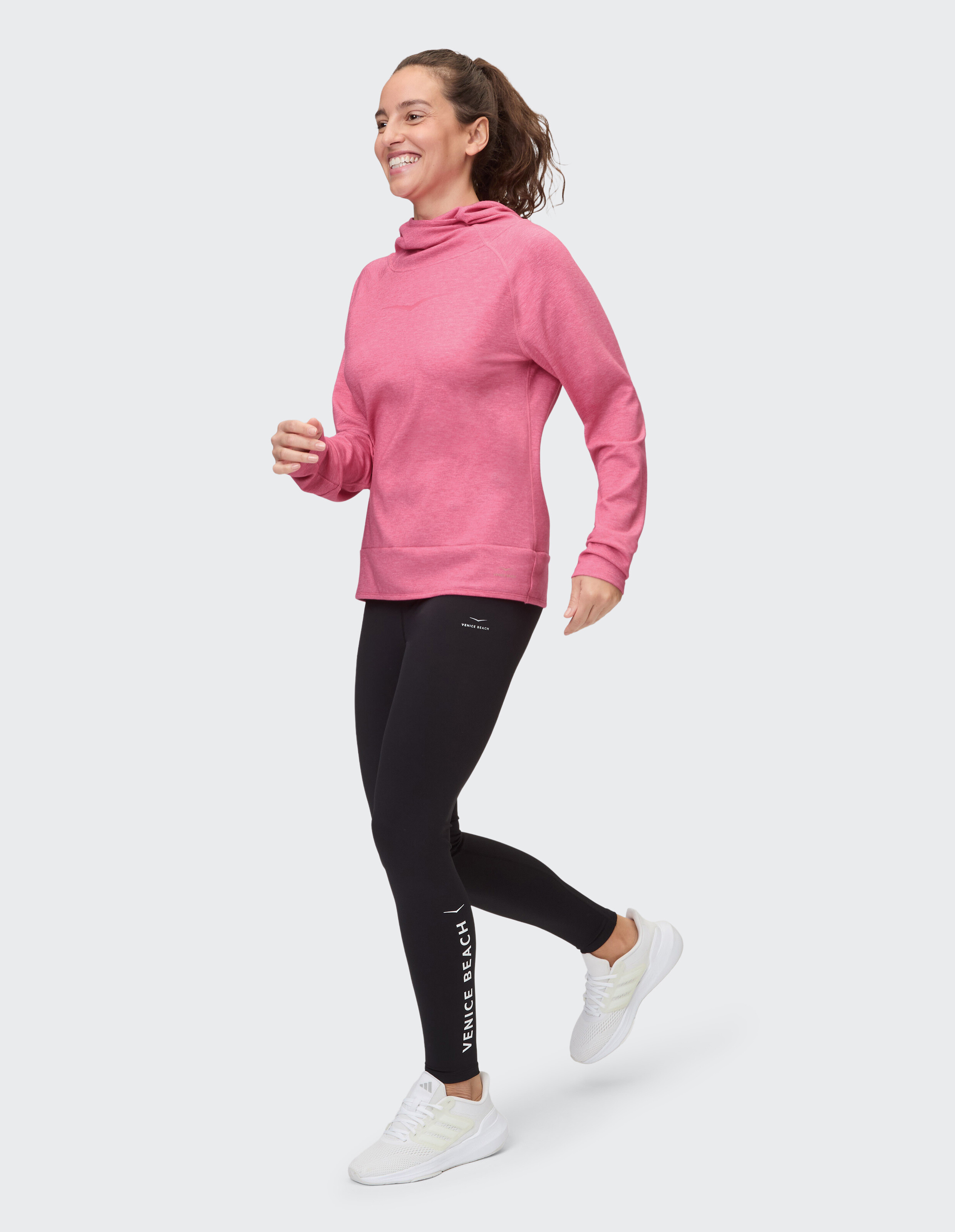 Frau in rosa Kapuzenpullover und schwarzen Leggings beim Joggen, lässiger, sportlicher Stil.