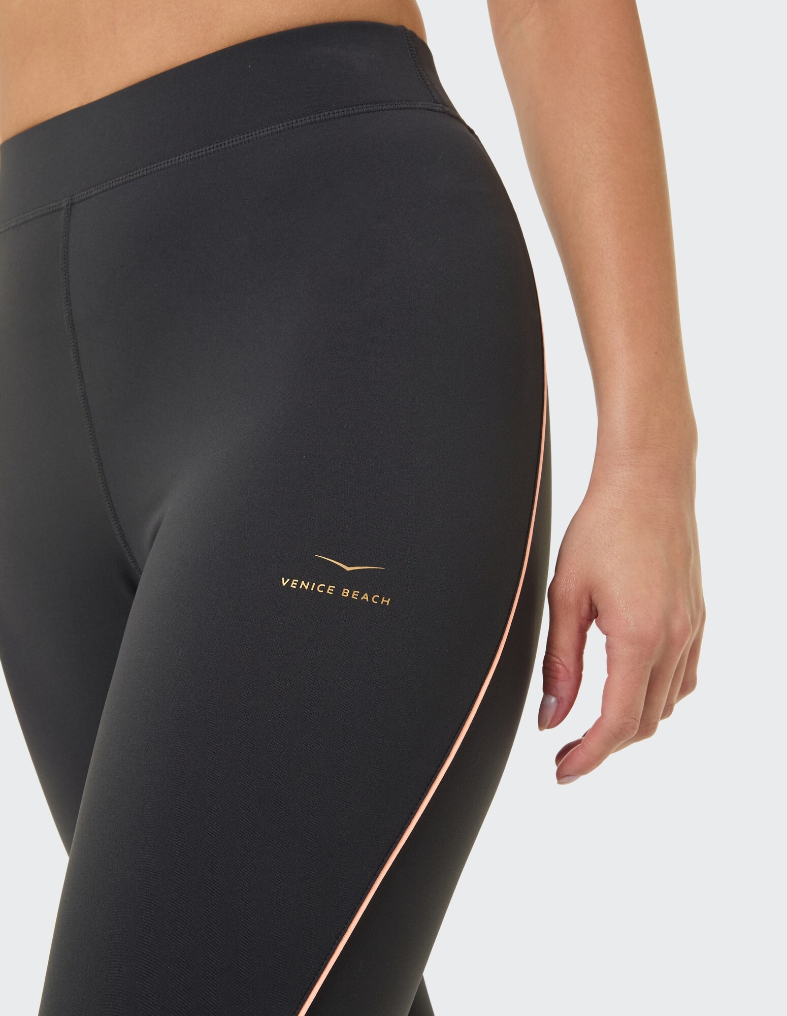 Nahaufnahme einer schwarzen Leggings mit rosa Seitenstreifen und Venice Beach-Logo.