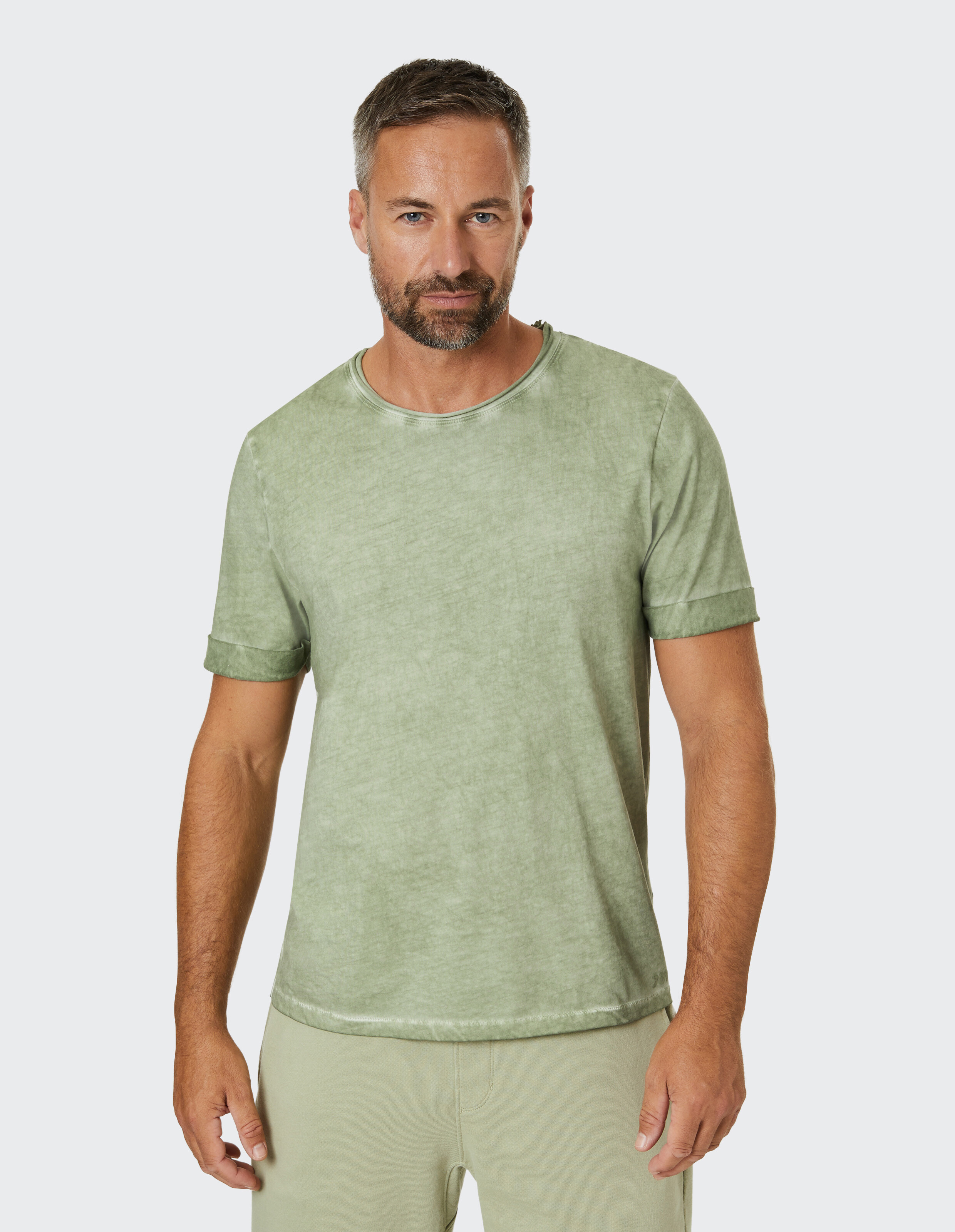 Mann trägt ein salbeigrünes Freizeit-T-Shirt mit Vintage-Waschung.