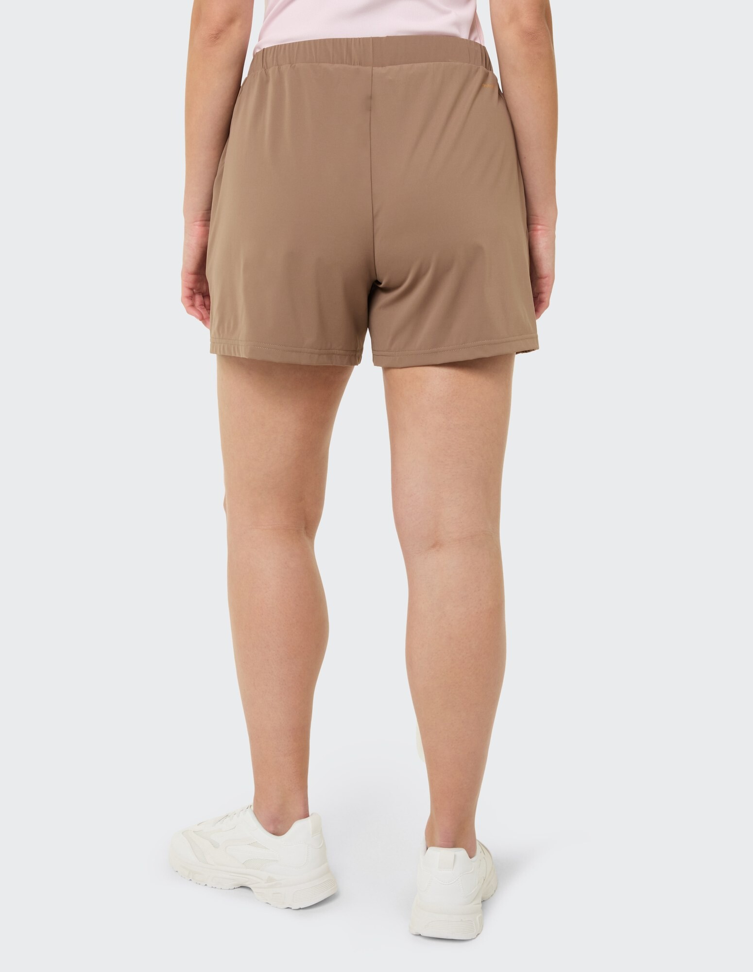 Rückansicht einer Frau in braunen Freizeitshorts und weißen Turnschuhen, perfekt zum Entspannen.