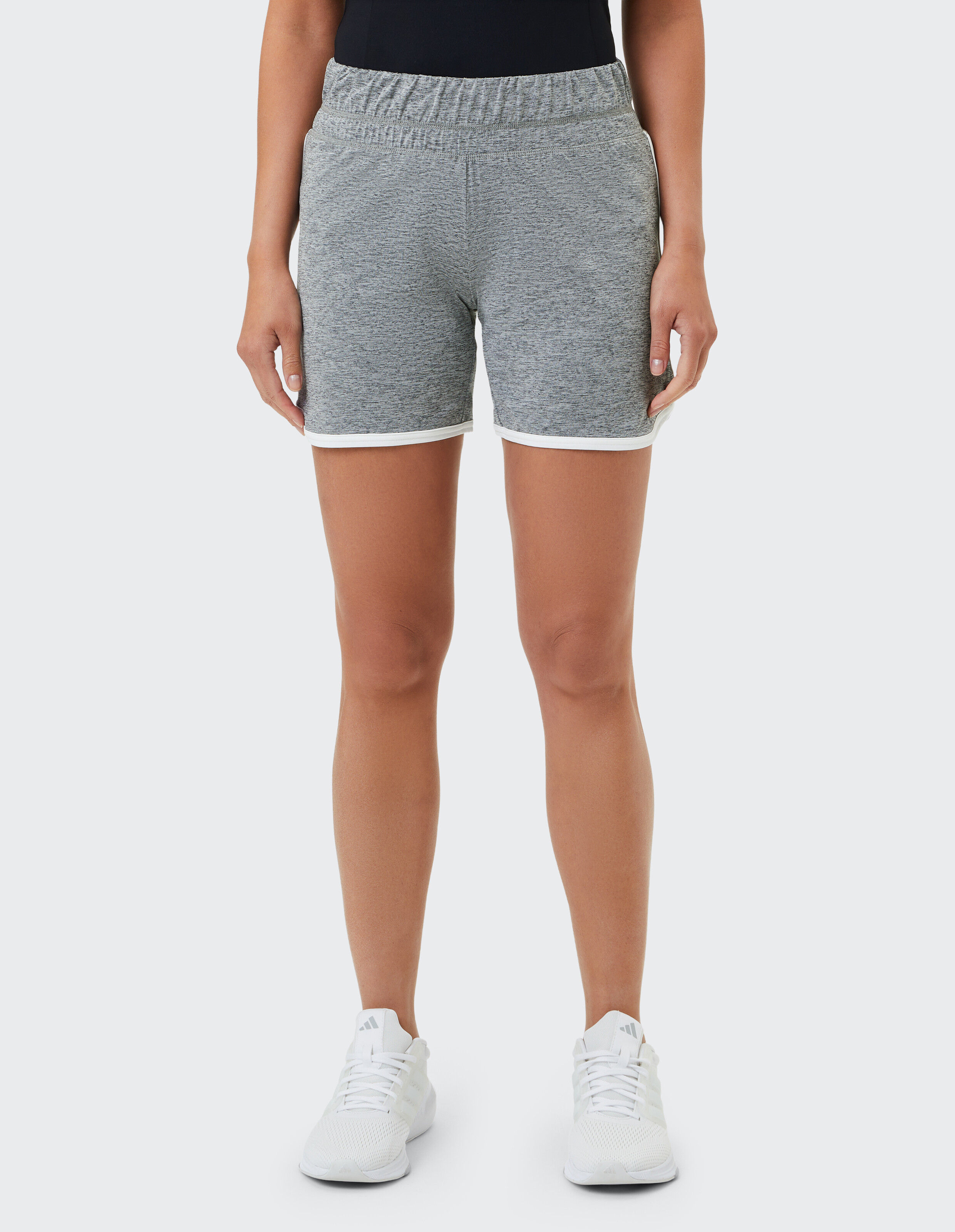 Frau trägt graue Melange-Lounge-Shorts mit weißem Besatz für lässigen Komfort.